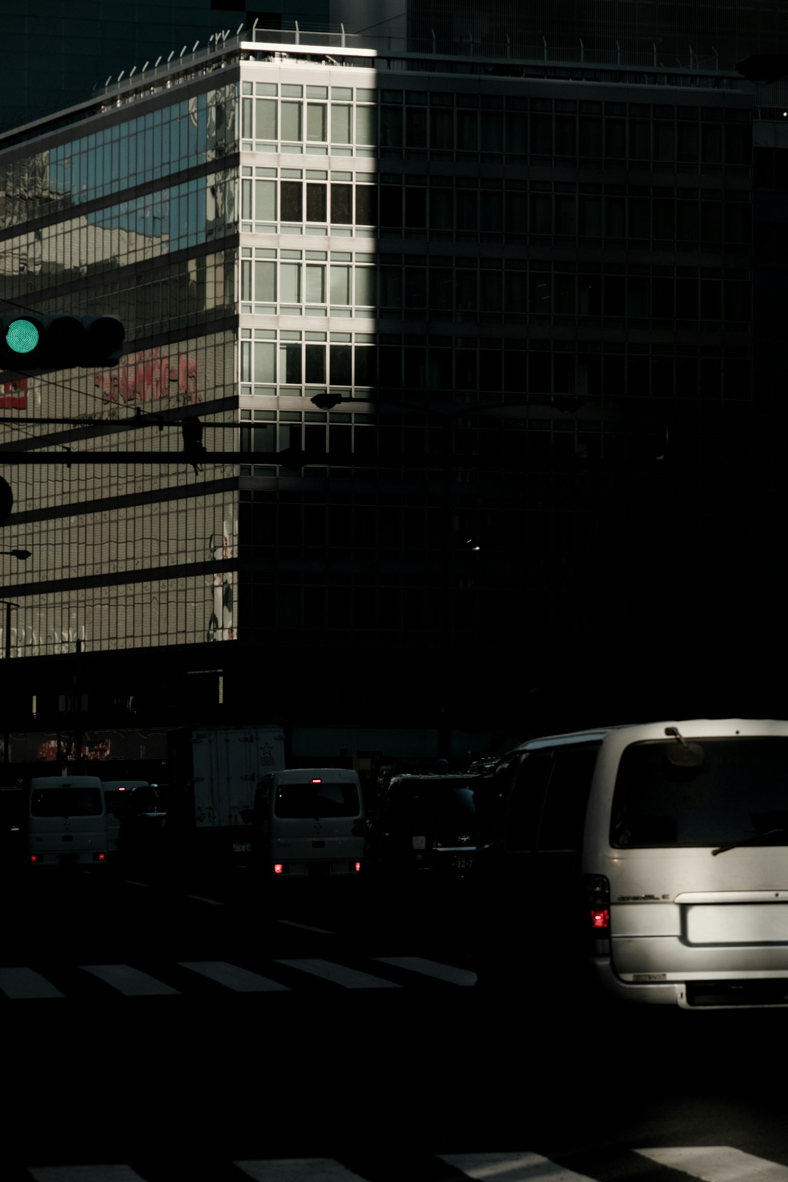 Traffic at an urban intersection with building reflections