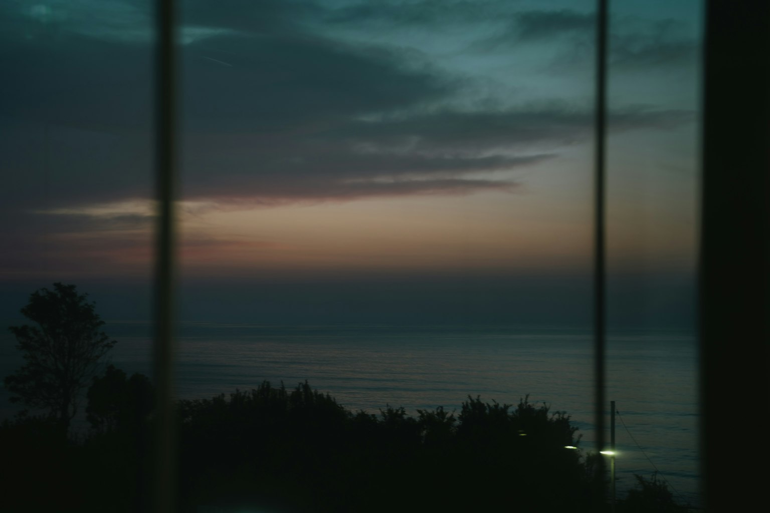 Sunset view over the ocean with colorful clouds seen through a window