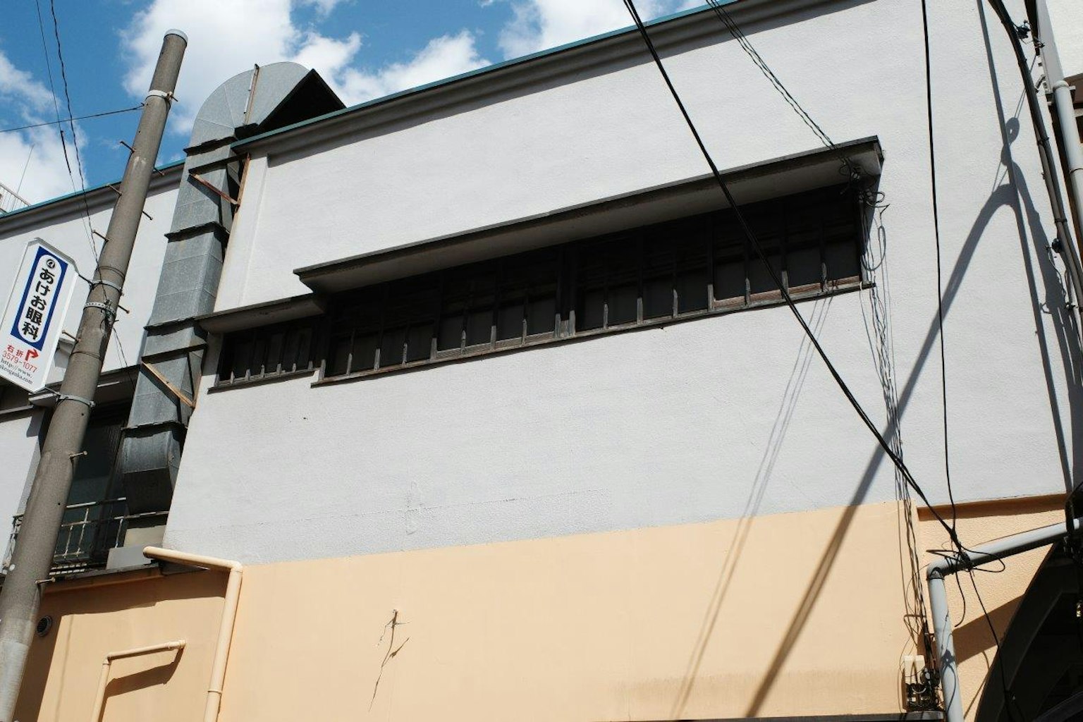 灰色建築外觀，帶有黑色窗戶和電線杆