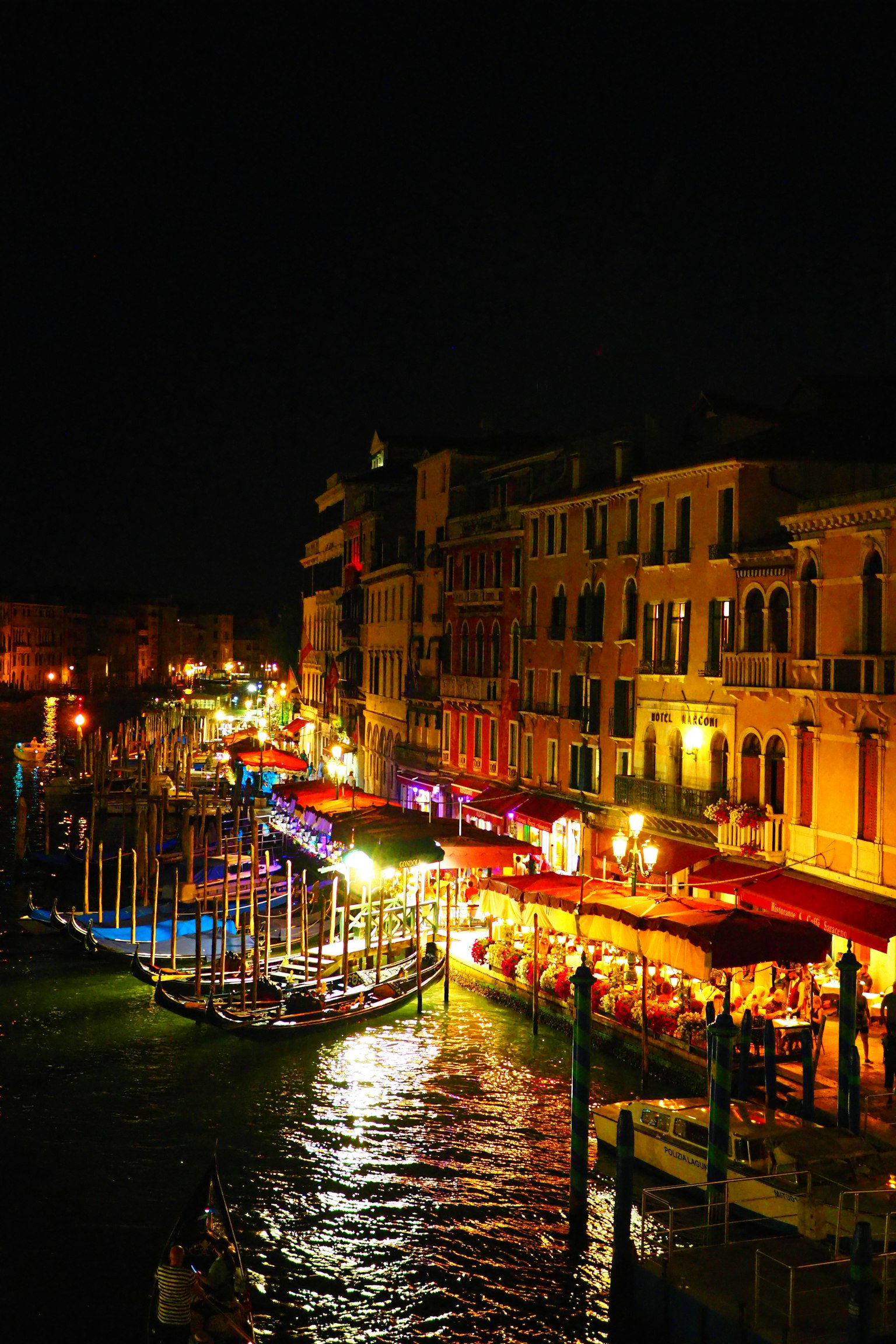 Khung cảnh đêm của kênh Venice với quán cà phê sáng đèn và thuyền