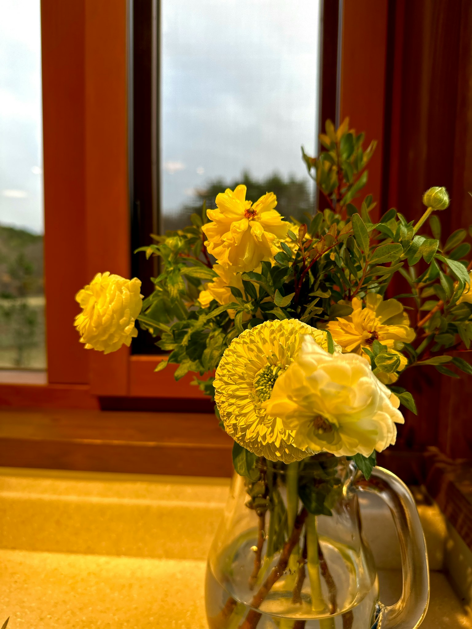 Ein Strauß gelber Blumen neben einem Fenster
