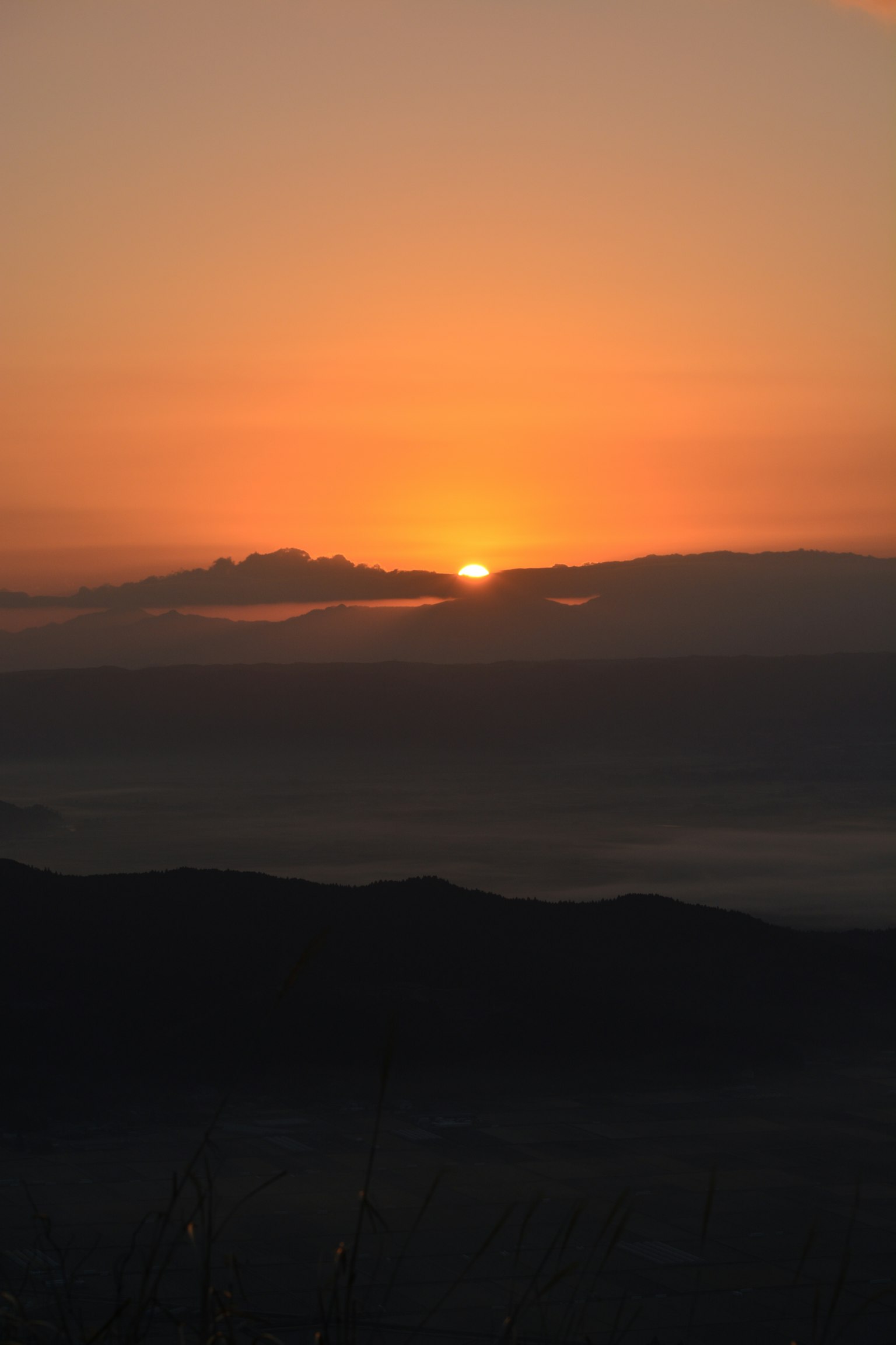 Un amanecer sereno sobre las montañas con un cielo naranja suave