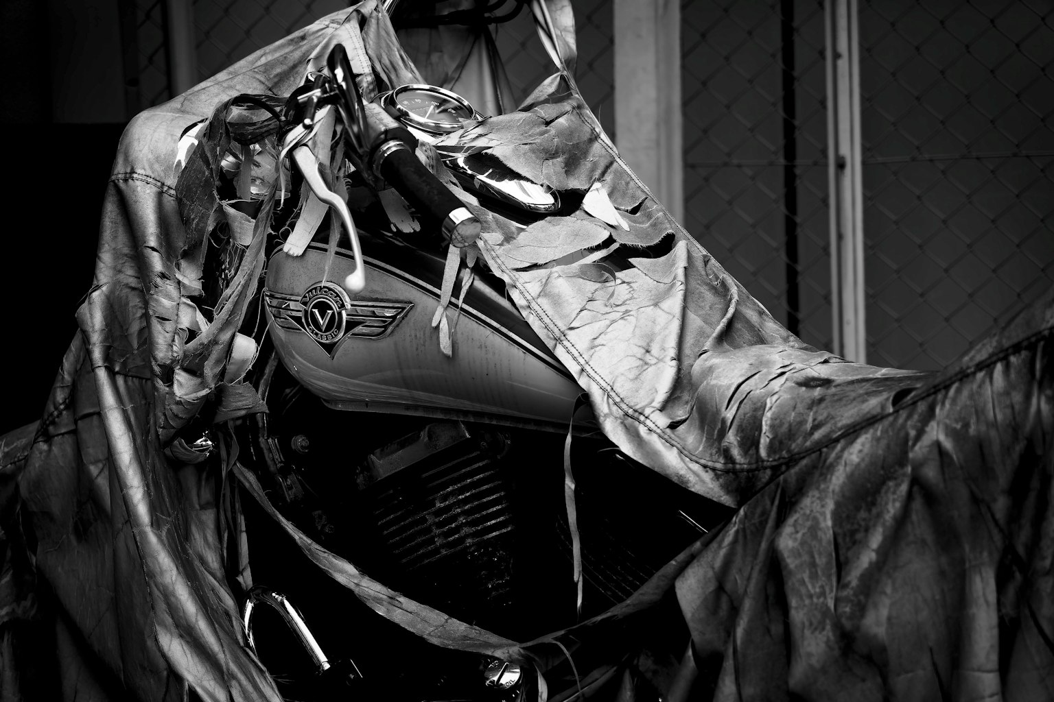Moto noir et blanc partiellement couverte par une bâche