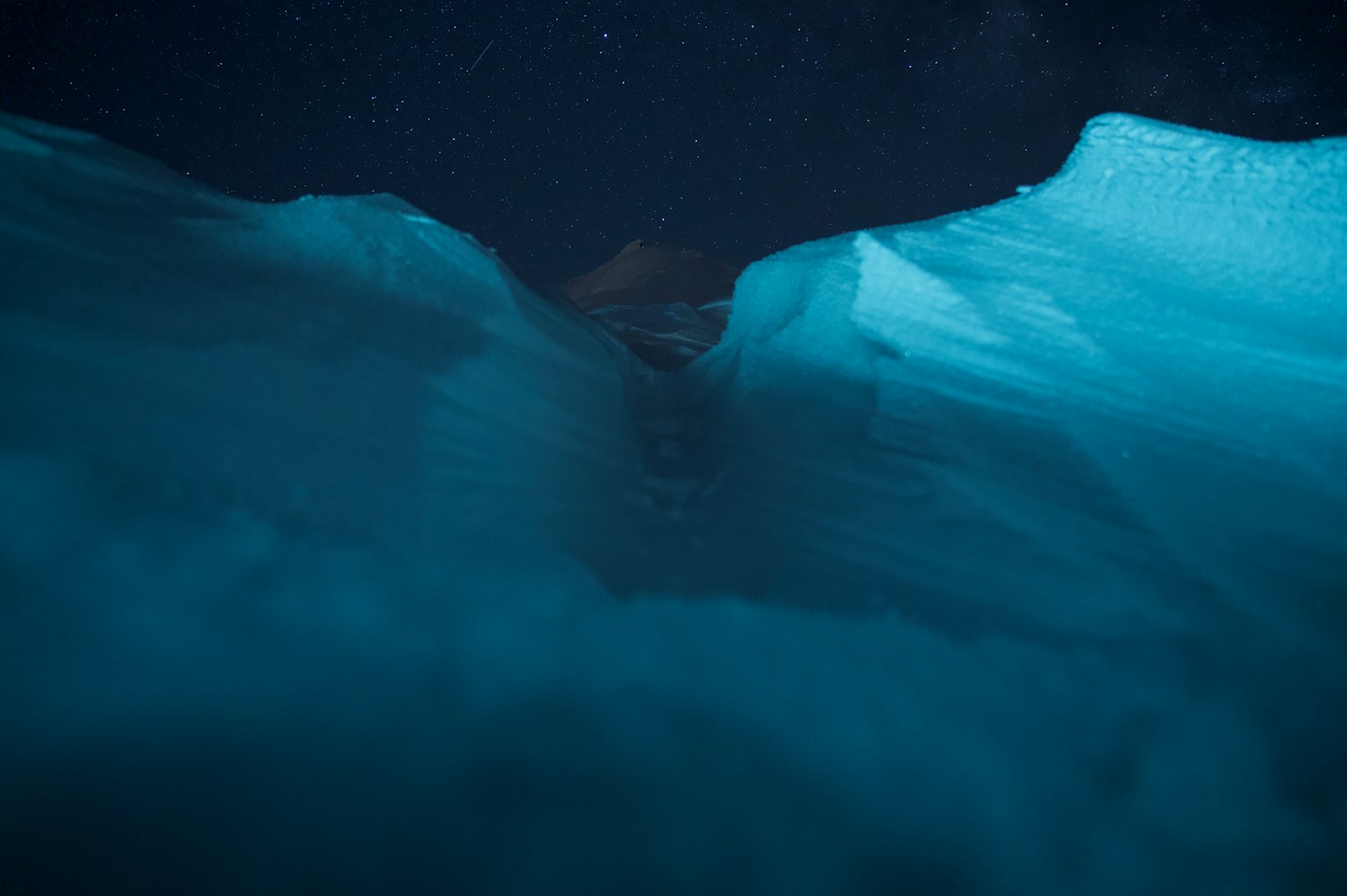 Crack in blue ice with starry night background