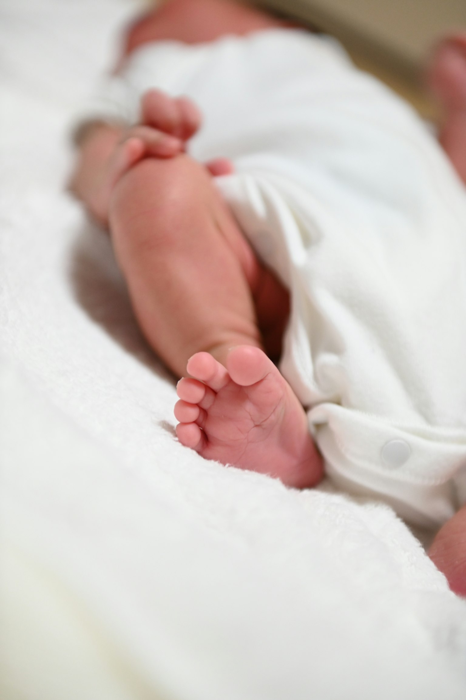 Gambar dekat kaki bayi dibungkus kain putih