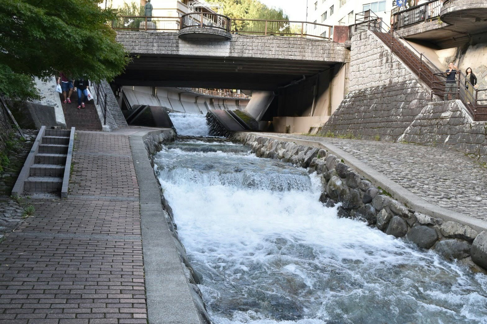 石積みの水路を流れる小さな滝のある都市の景観