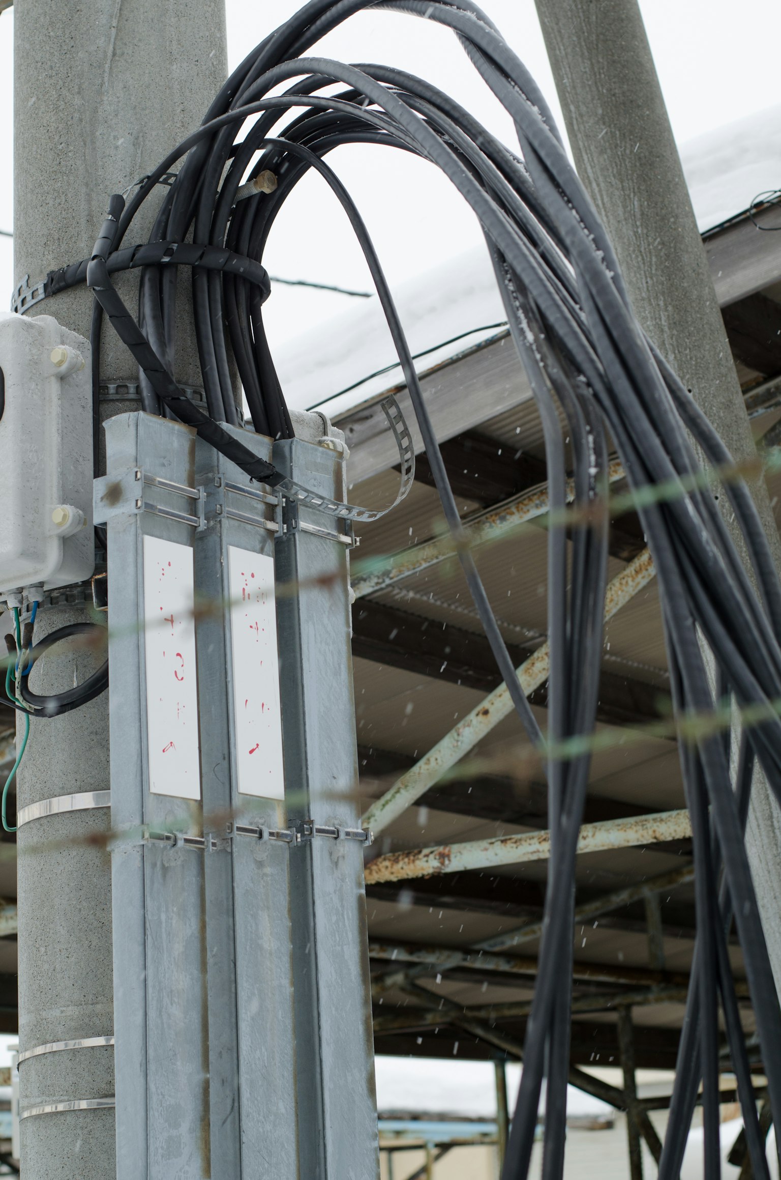 Black cables tangled around a metal pole