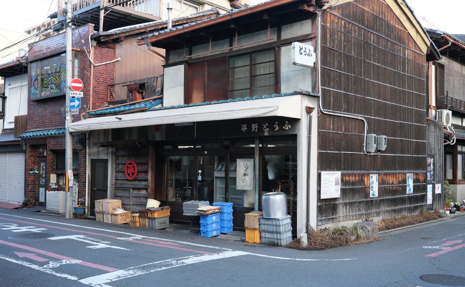 Extérieur d'un vieux magasin japonais avec une façade de type entrepôt et une porte en bois située à un coin de rue
