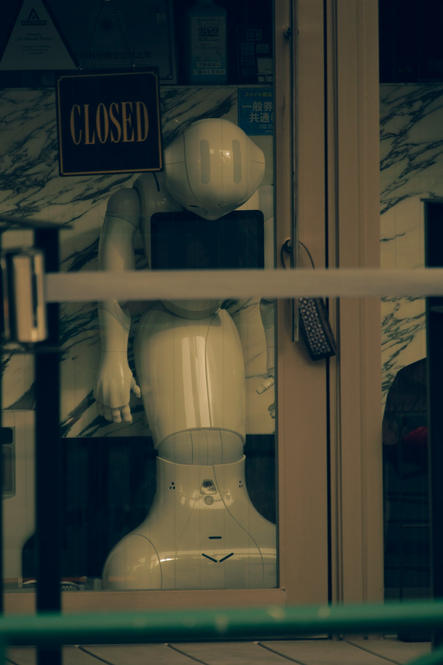 Un mannequin robot blanc à l'intérieur d'un magasin avec un panneau fermé