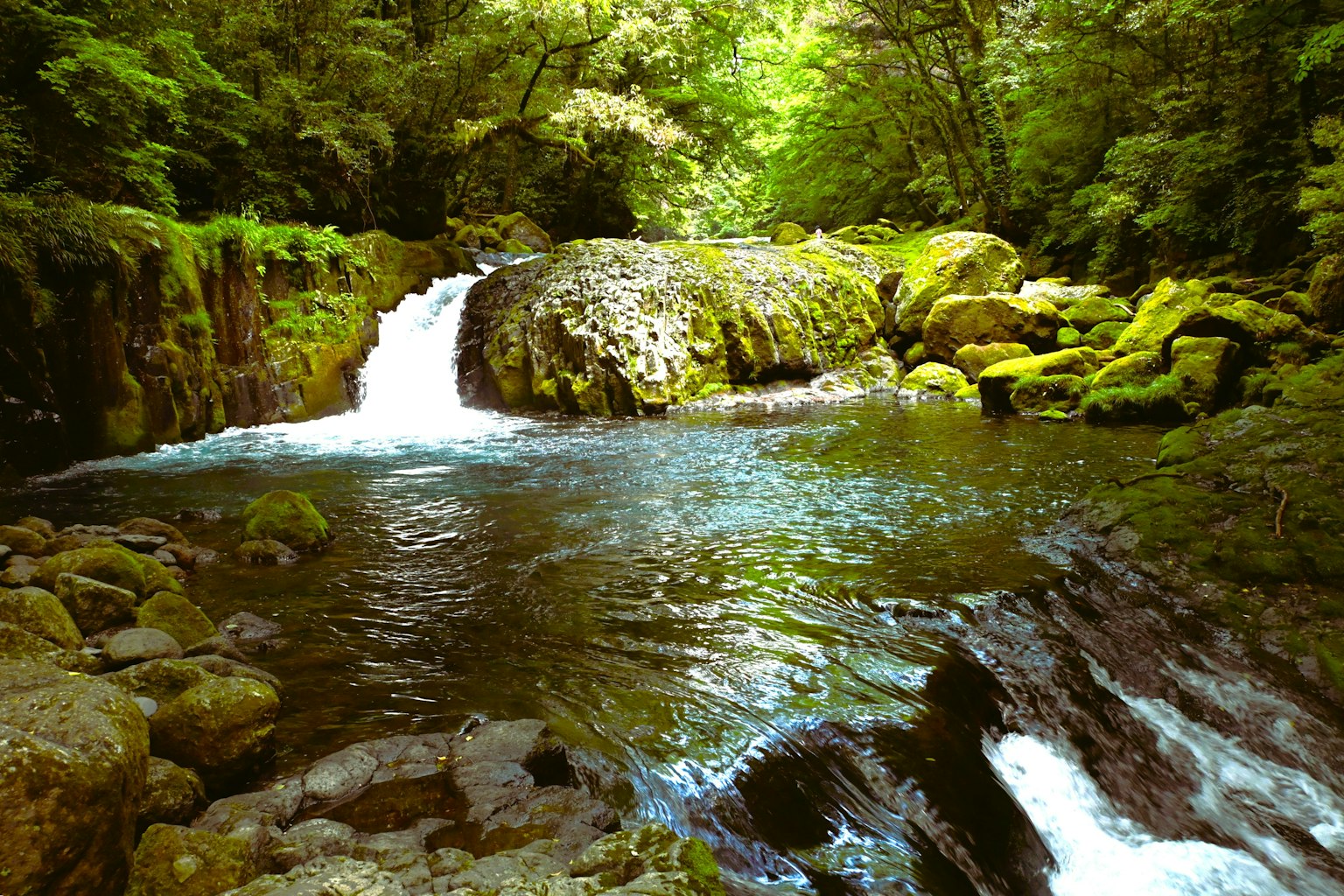 Eine ruhige Flusslandschaft mit einem Wasserfall, umgeben von üppigem Grün