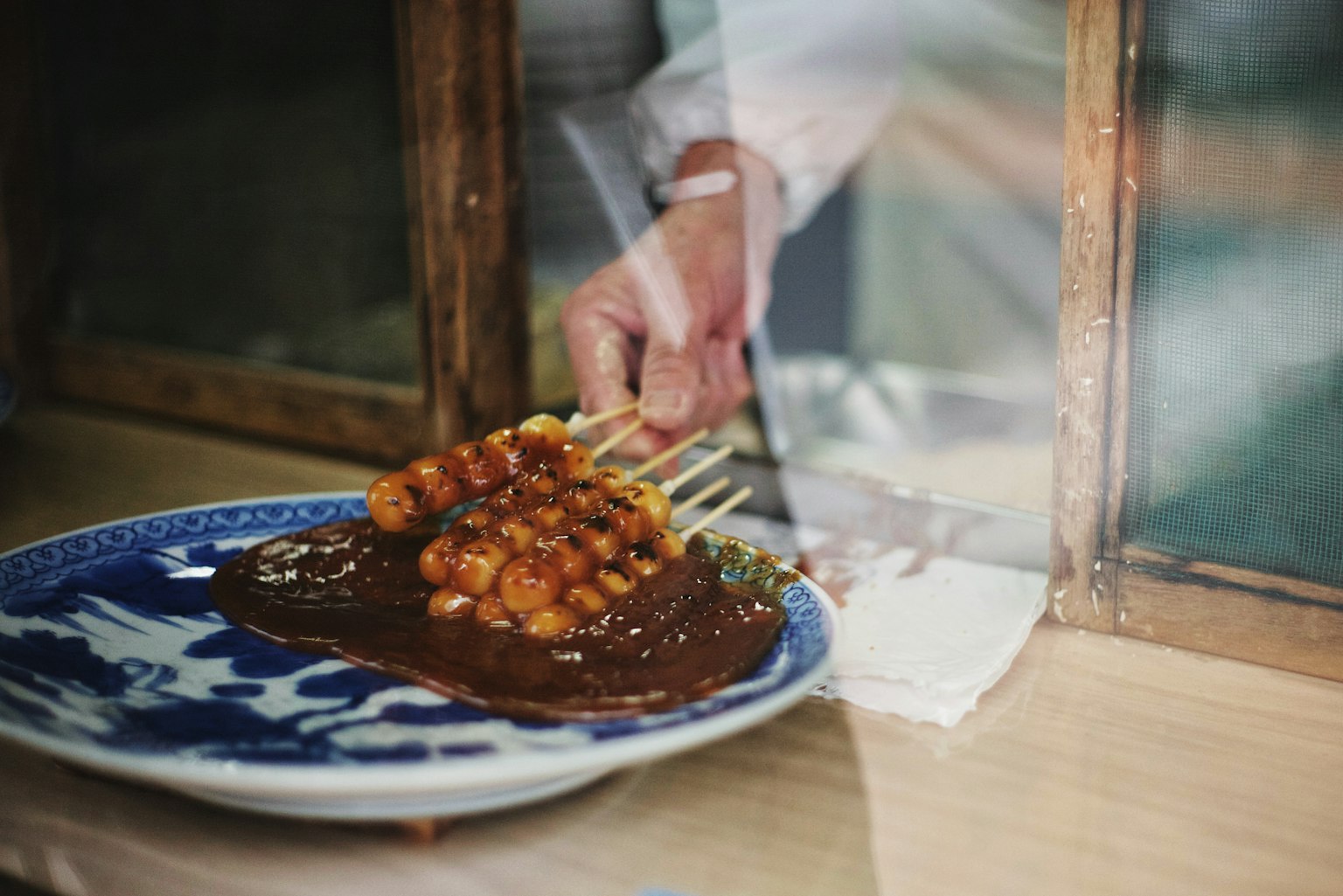 Une main plaçant de la nourriture en brochettes sur une assiette