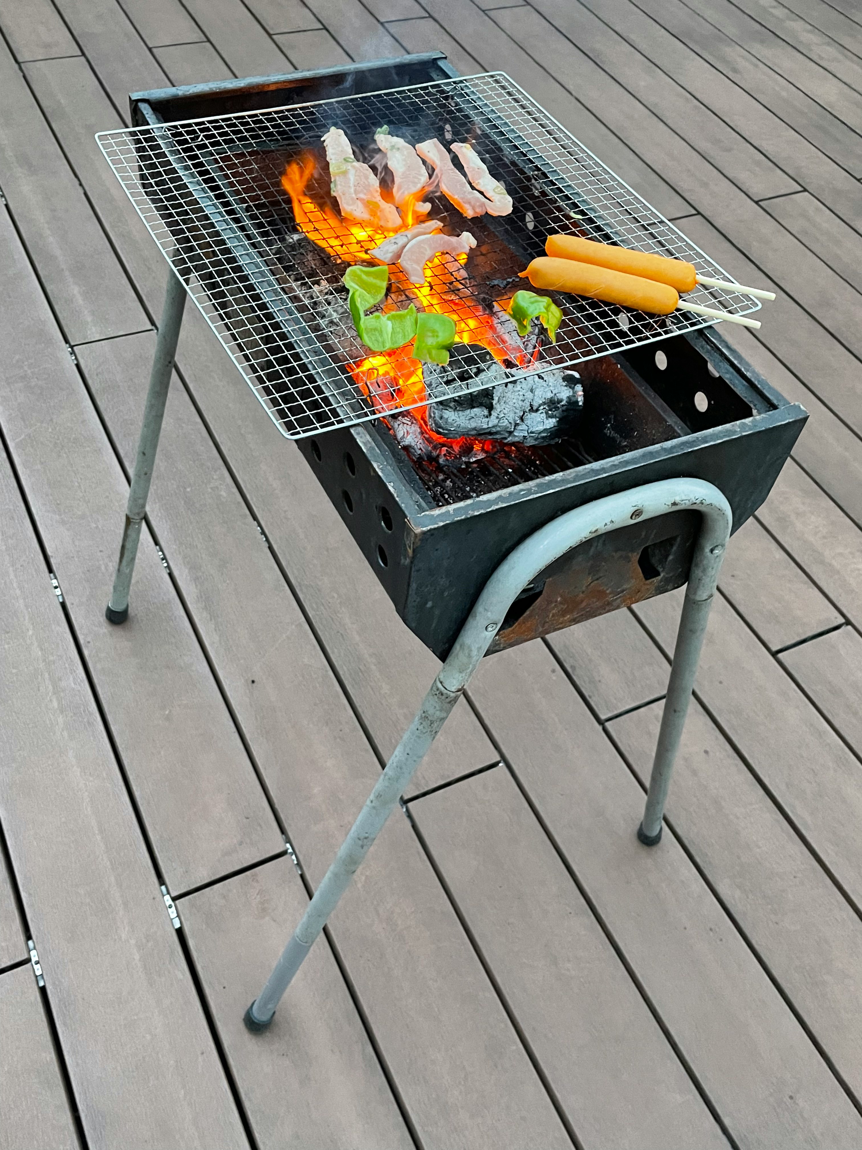 Vỉ nướng BBQ ngoài trời với ngọn lửa và xúc xích