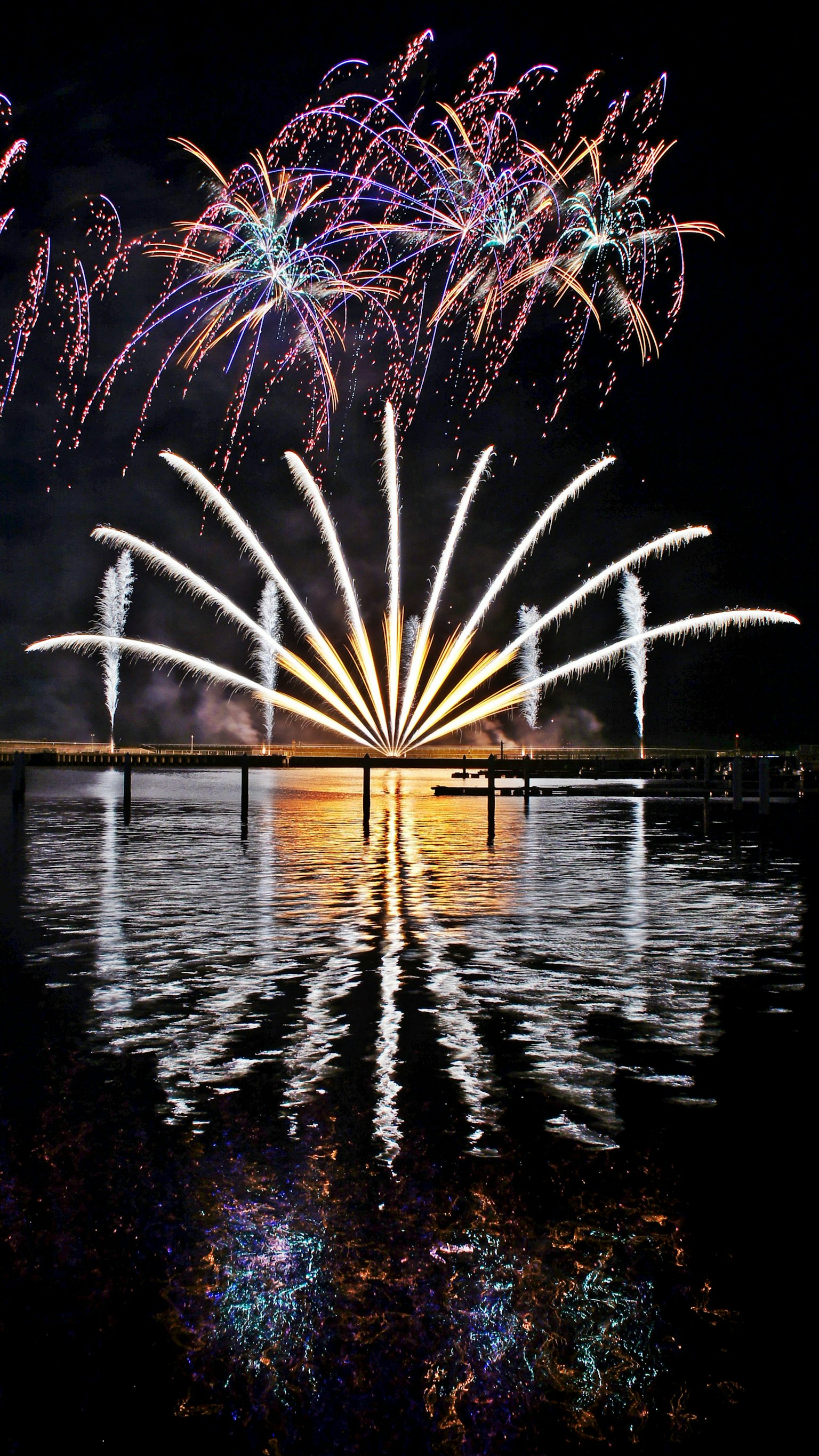 Spectacular fireworks display lighting up the night sky with colorful reflections on the water