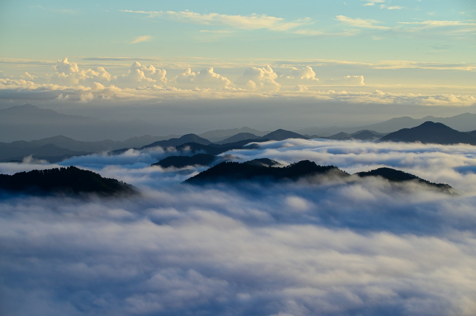 Impresionante paisaje de montañas flotando sobre un mar de nubes