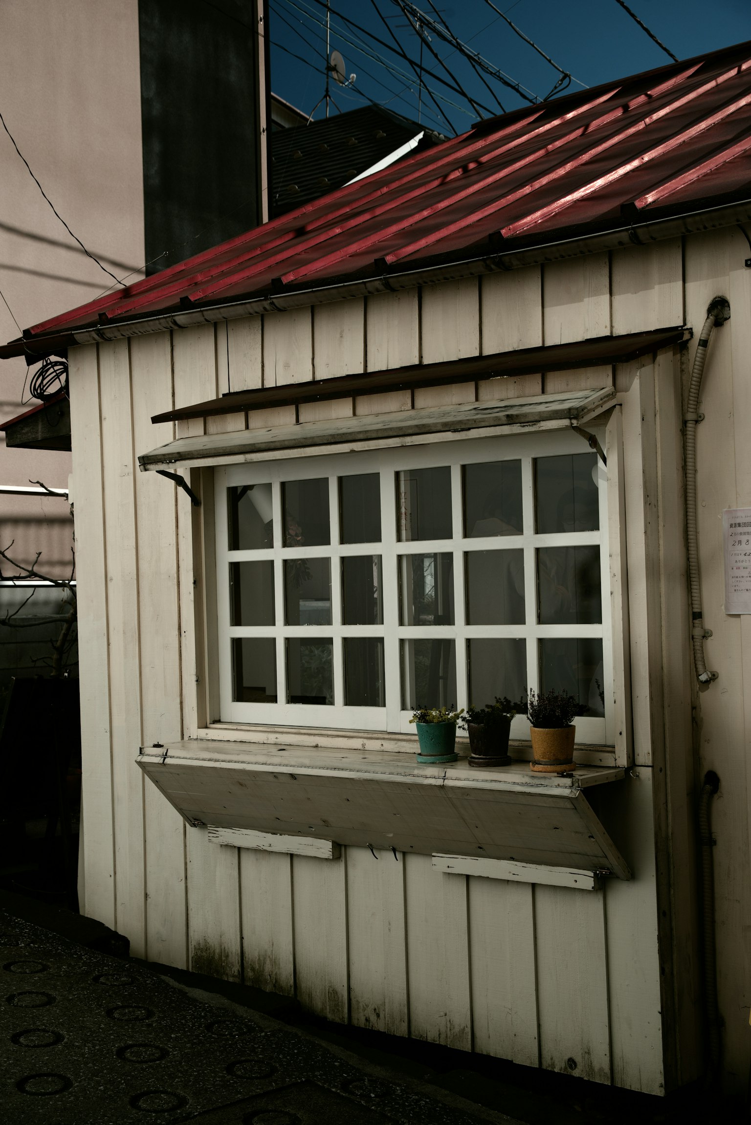 Kleine Hütte mit weißer Holzaußenwand und rotem Dach mit einem Fenster