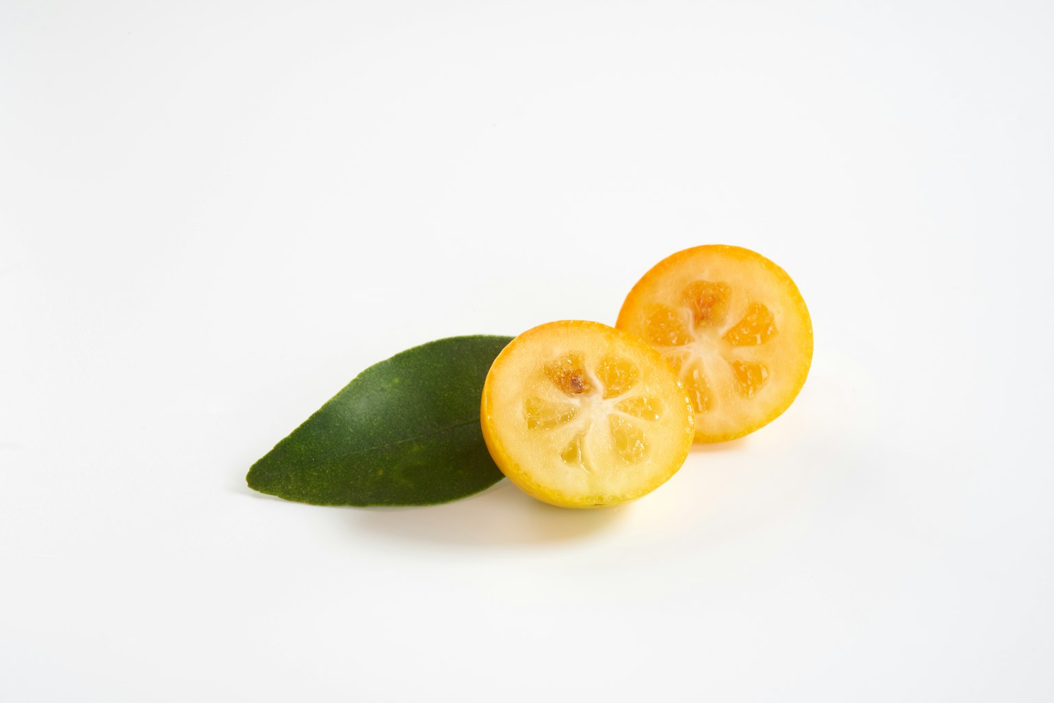 Buah calamansi yang diiris dengan daun hijau di latar belakang putih