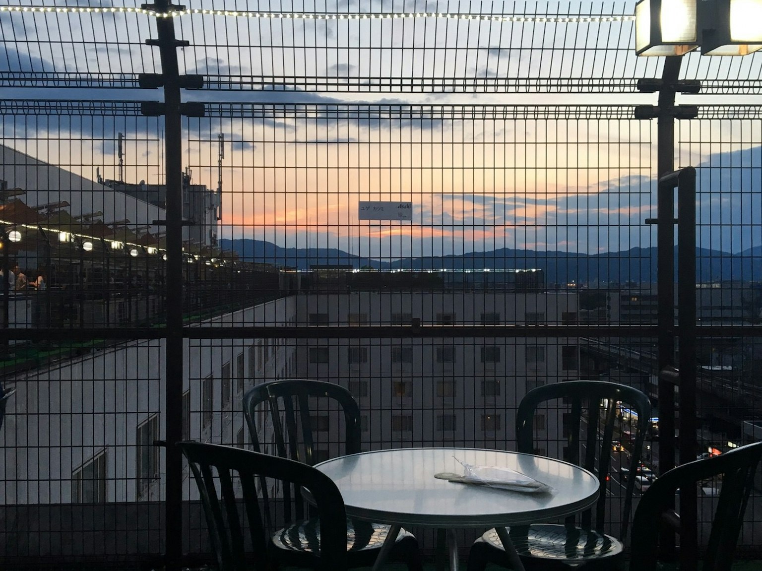 Terrasse sur le toit avec une table et des chaises surplombant un coucher de soleil