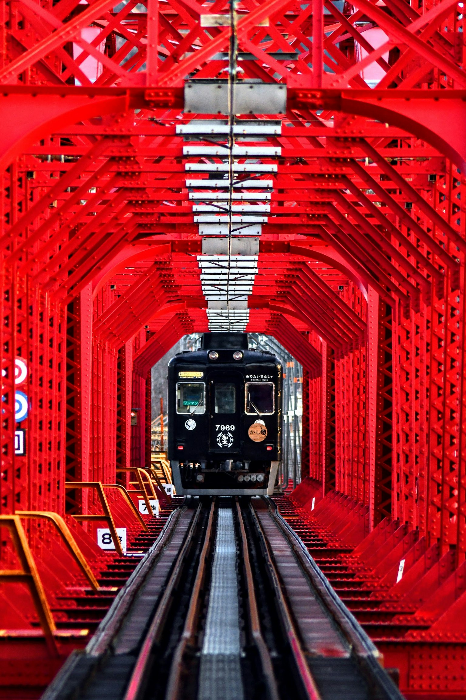 Treno nero che corre sotto un ponte rosso