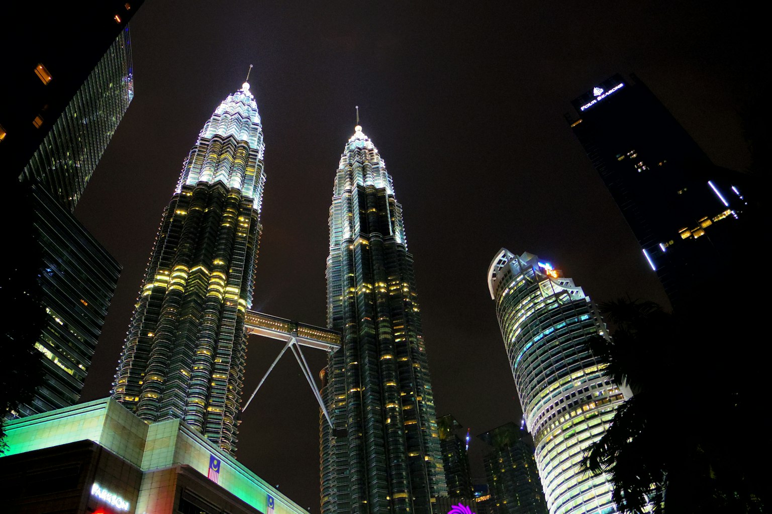 Pemandangan malam Menara Kembar Petronas di Kuala Lumpur dengan lampu terang dan gedung pencakar langit di sekitarnya