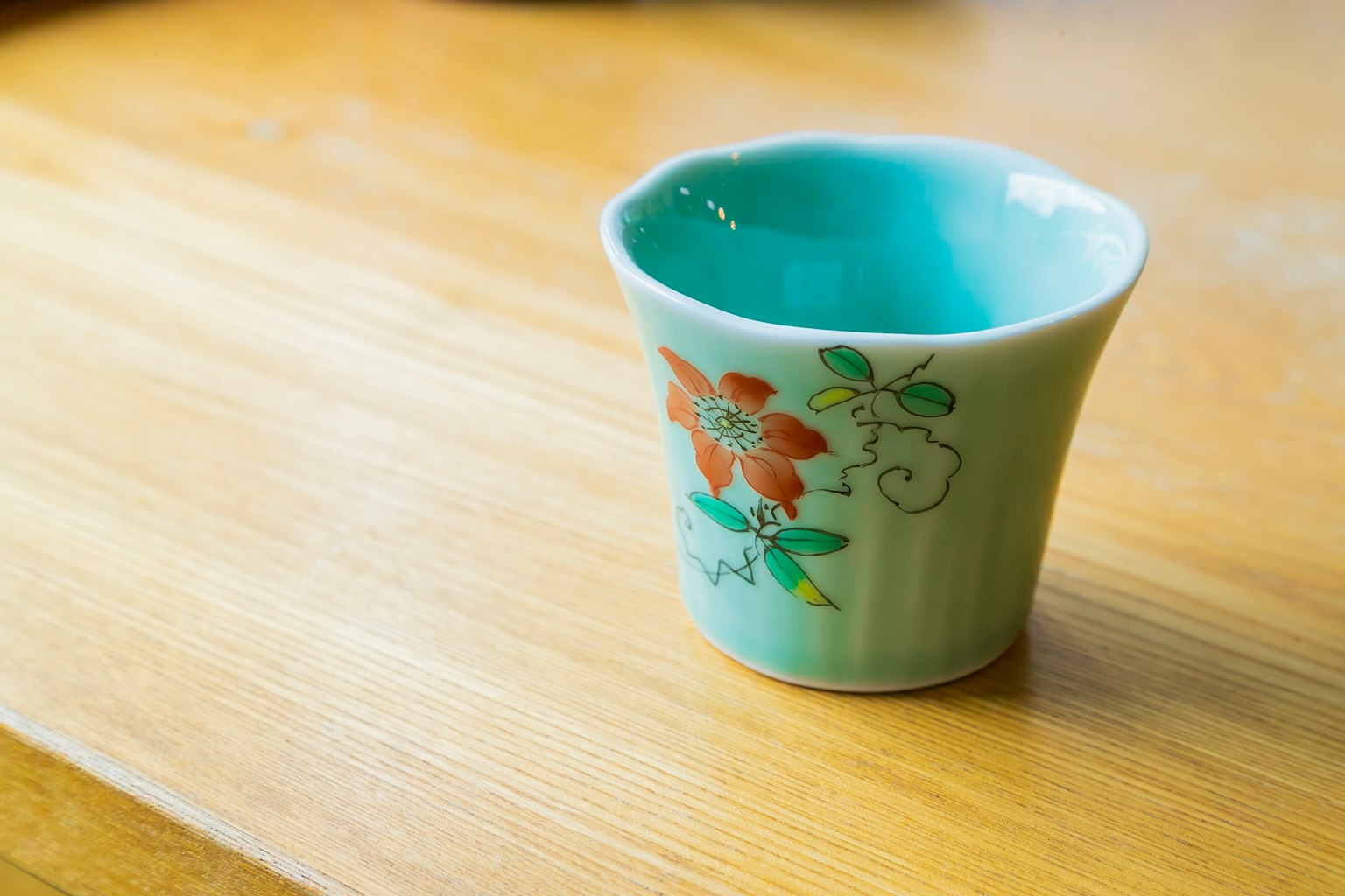 Ceramic cup with a turquoise interior and floral design