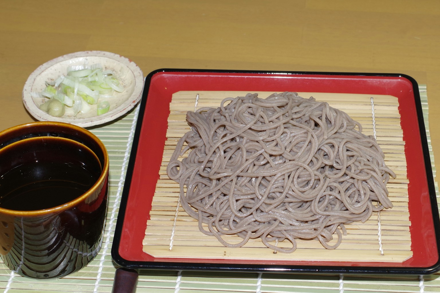 Plate of soba noodles with dipping sauce and sliced green onions in Japanese cuisine