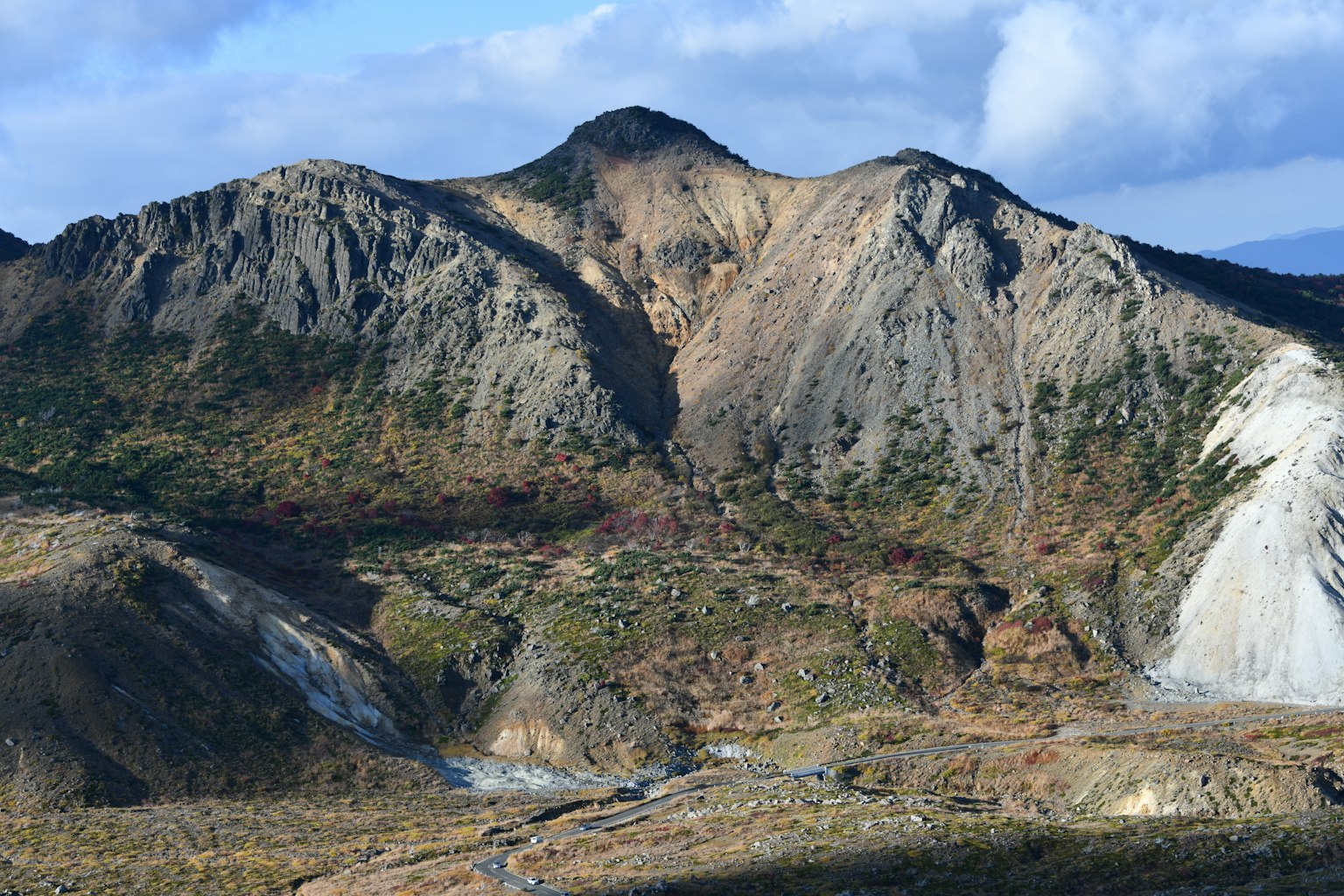 Berglandschaft mit felsigem Gelände und Grünflächen unter blauem Himmel