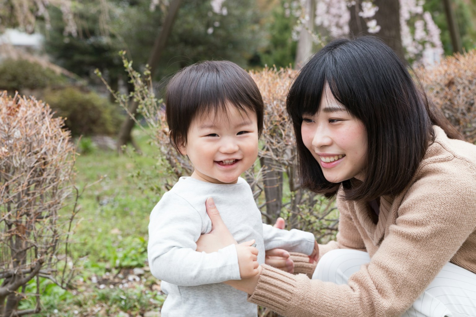 Close moment between a smiling child and mother in a park