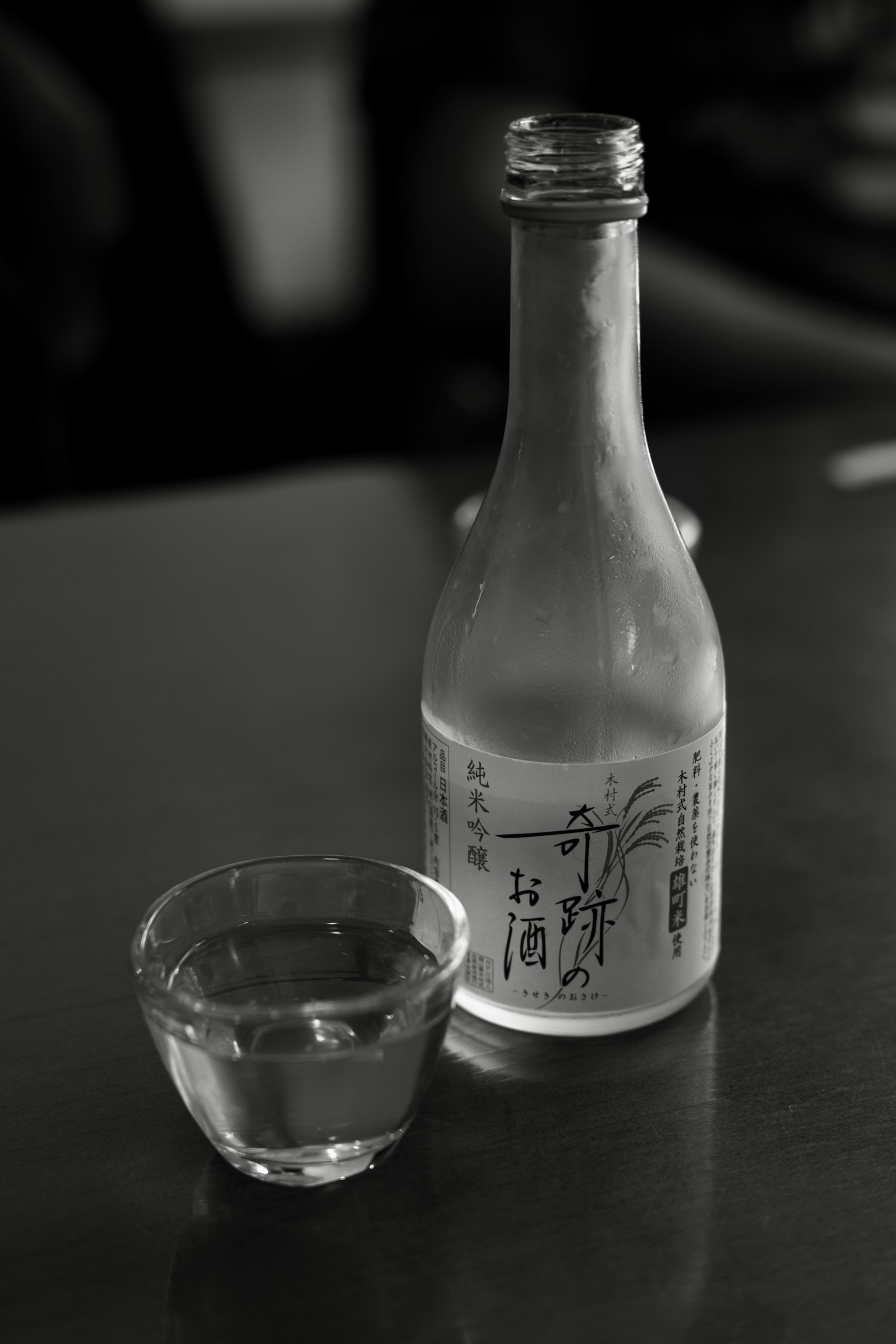 어두운 배경 위에 있는 사케 병과 작은 잔