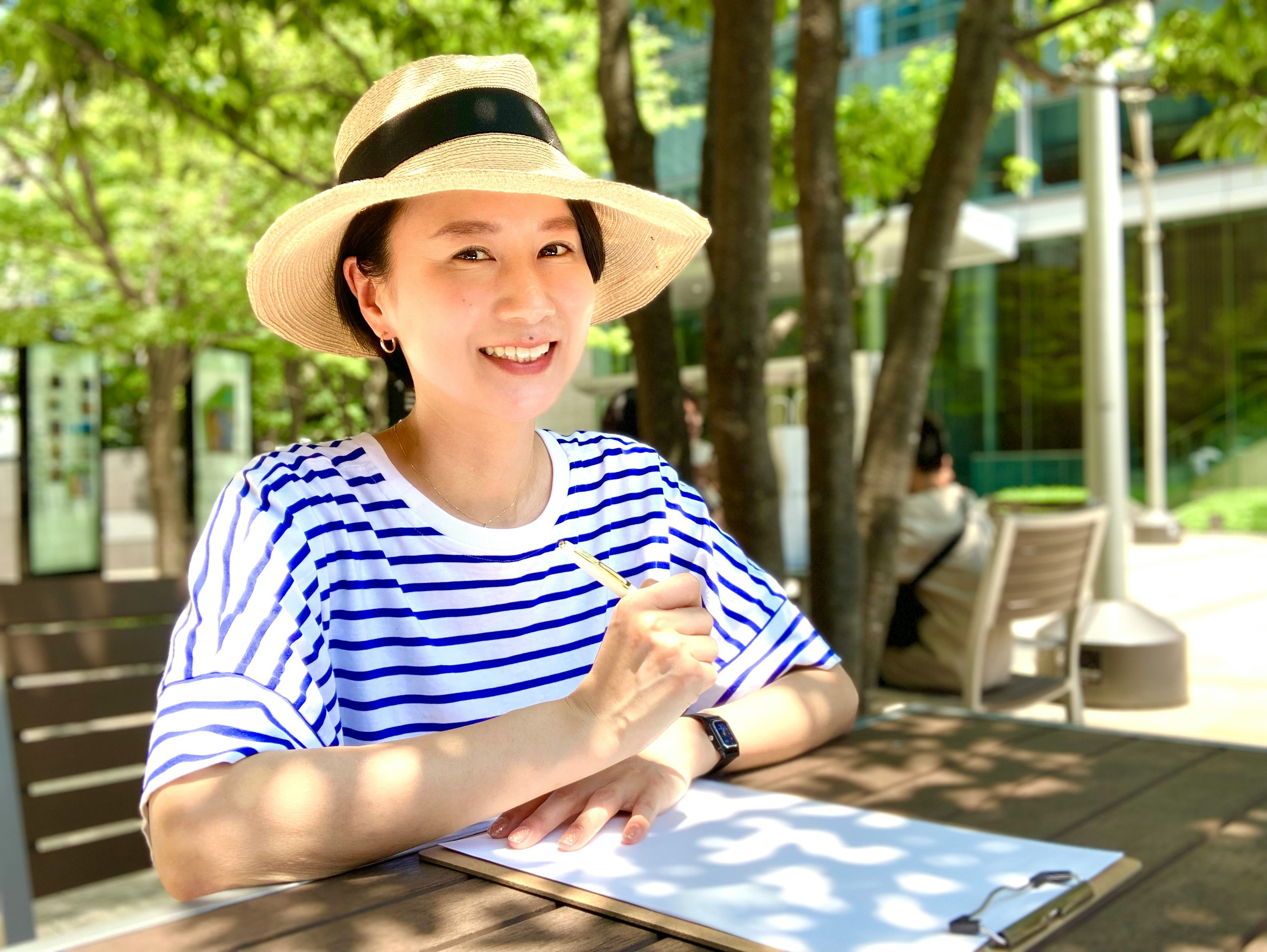 戴帽子的微笑女性坐在公園長椅上