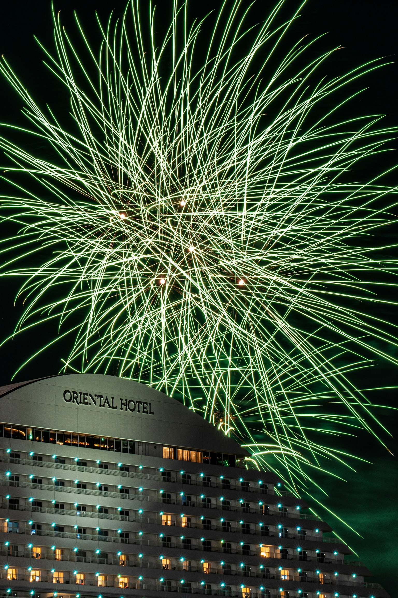 夜空に広がる花火とオリエンタルシティのホテルの外観