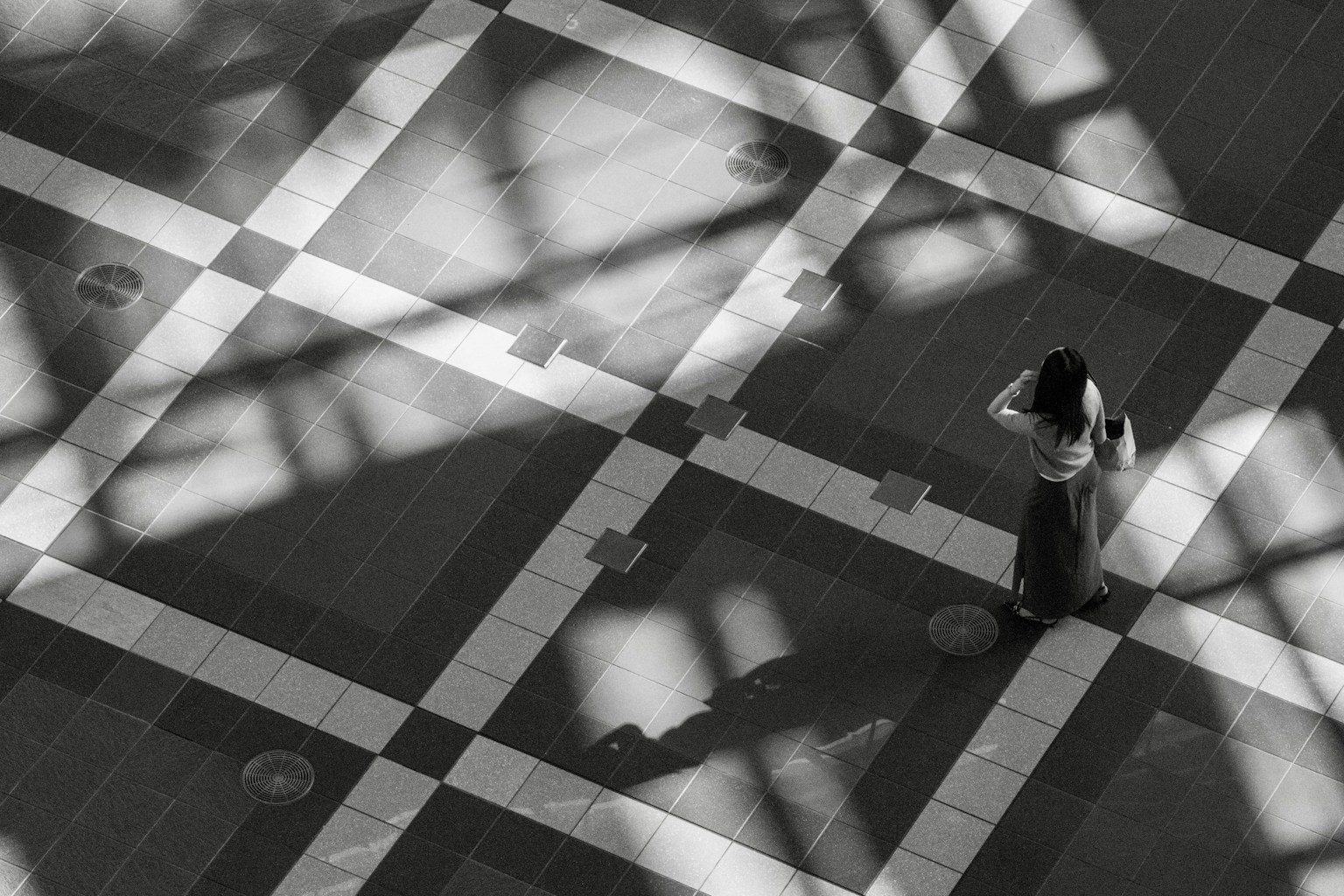 Eine Frau steht auf einem gemusterten Boden mit Schatten in Schwarz und Weiß
