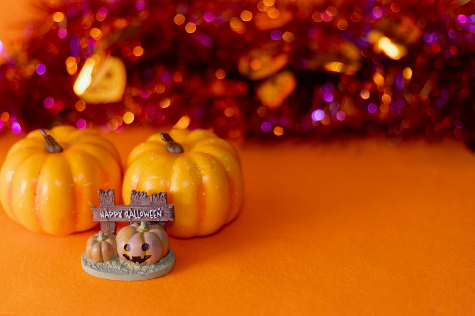 Dua labu kecil dengan dekorasi Halloween di latar belakang oranye