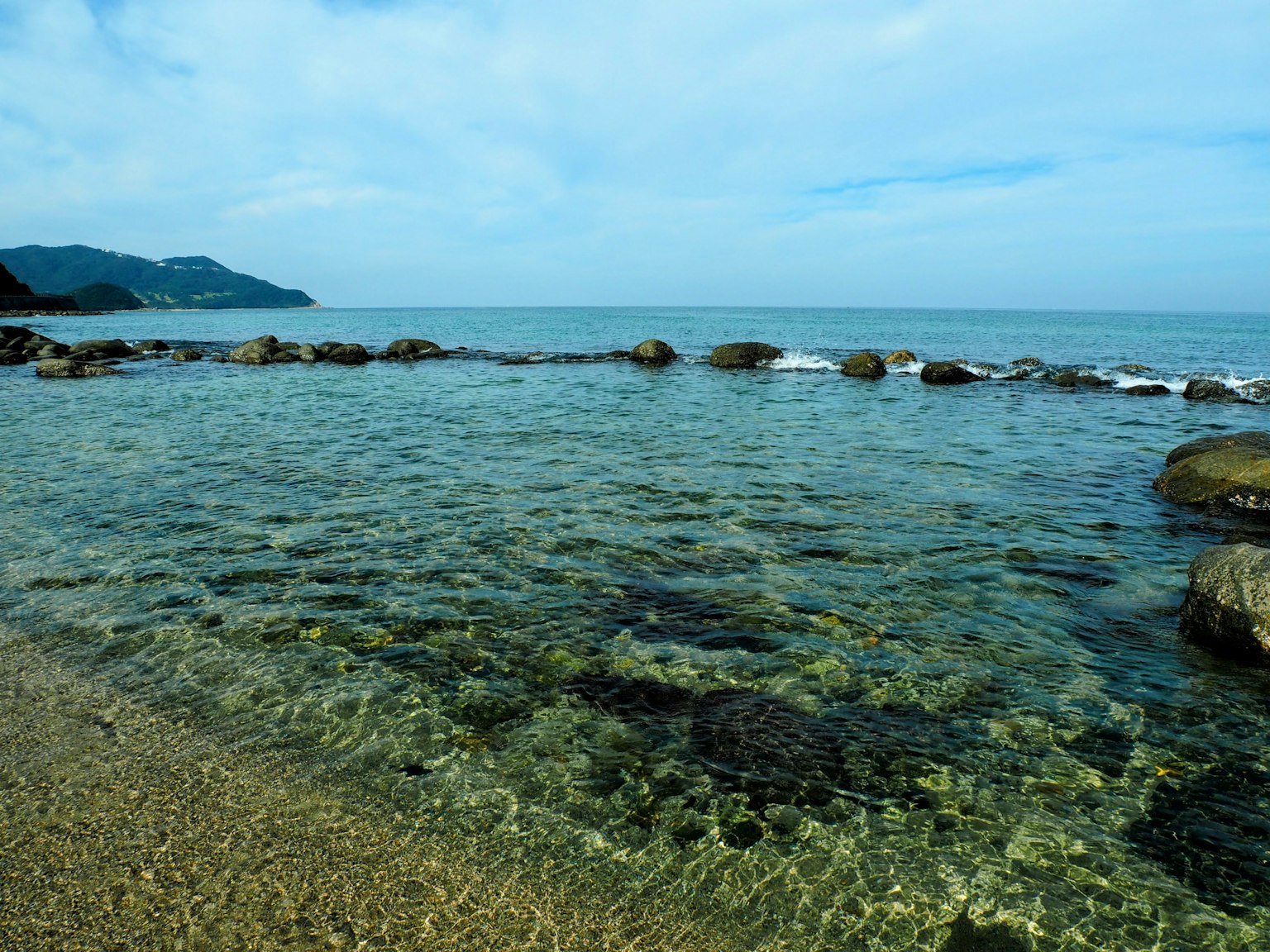 清澈的海水和沙滩场景 蓝天和远处的山脉可见