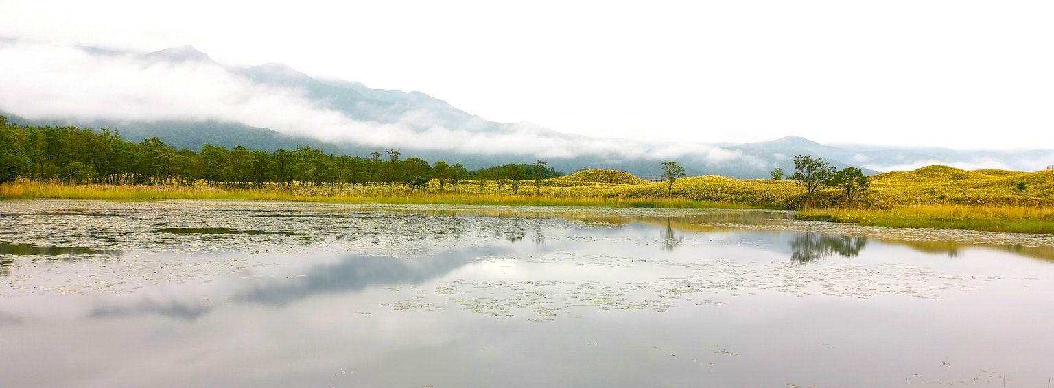 Lago tranquilo reflejando montañas y paisaje verde