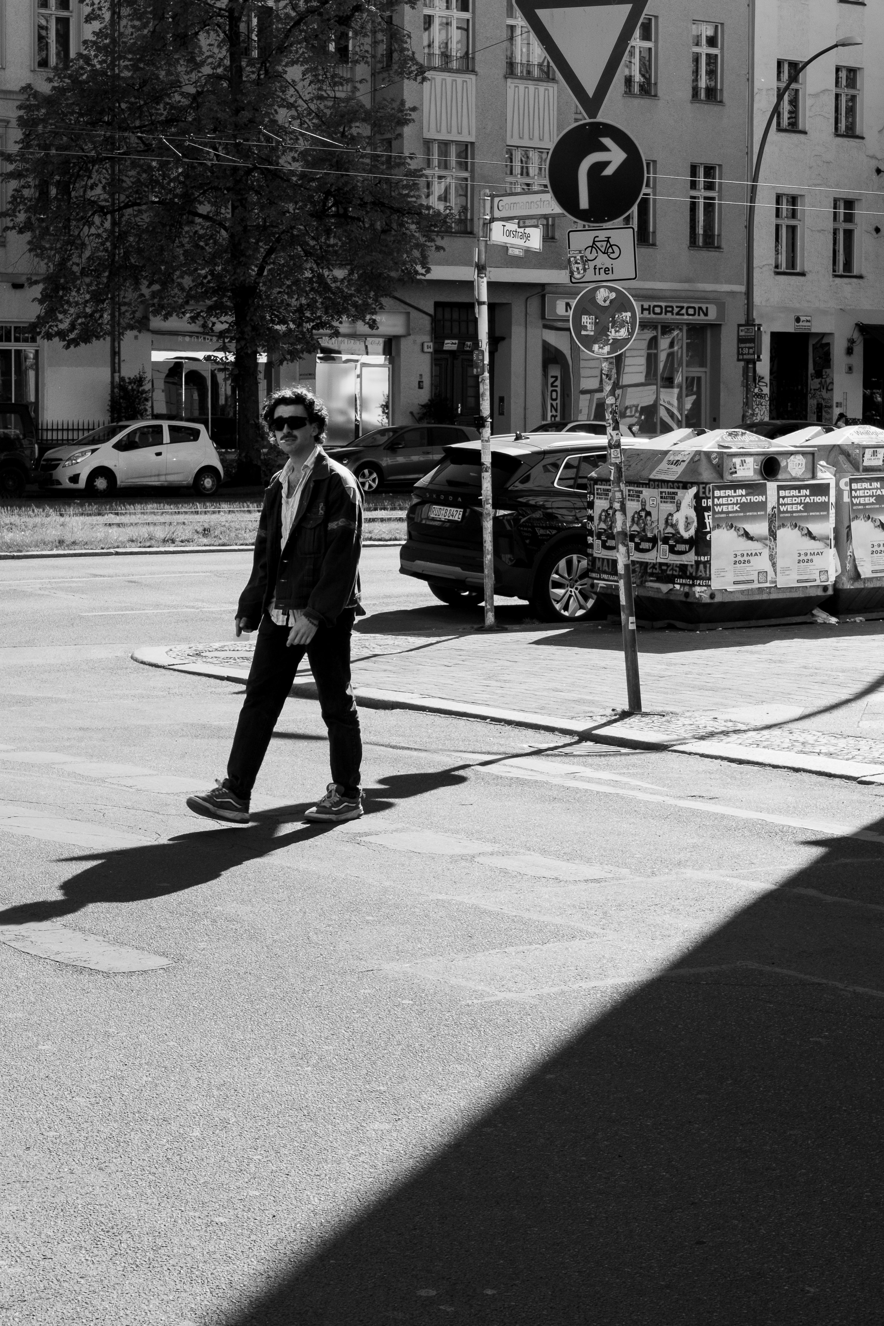 uomo in abito che cammina a un angolo di strada con insegna di carrello