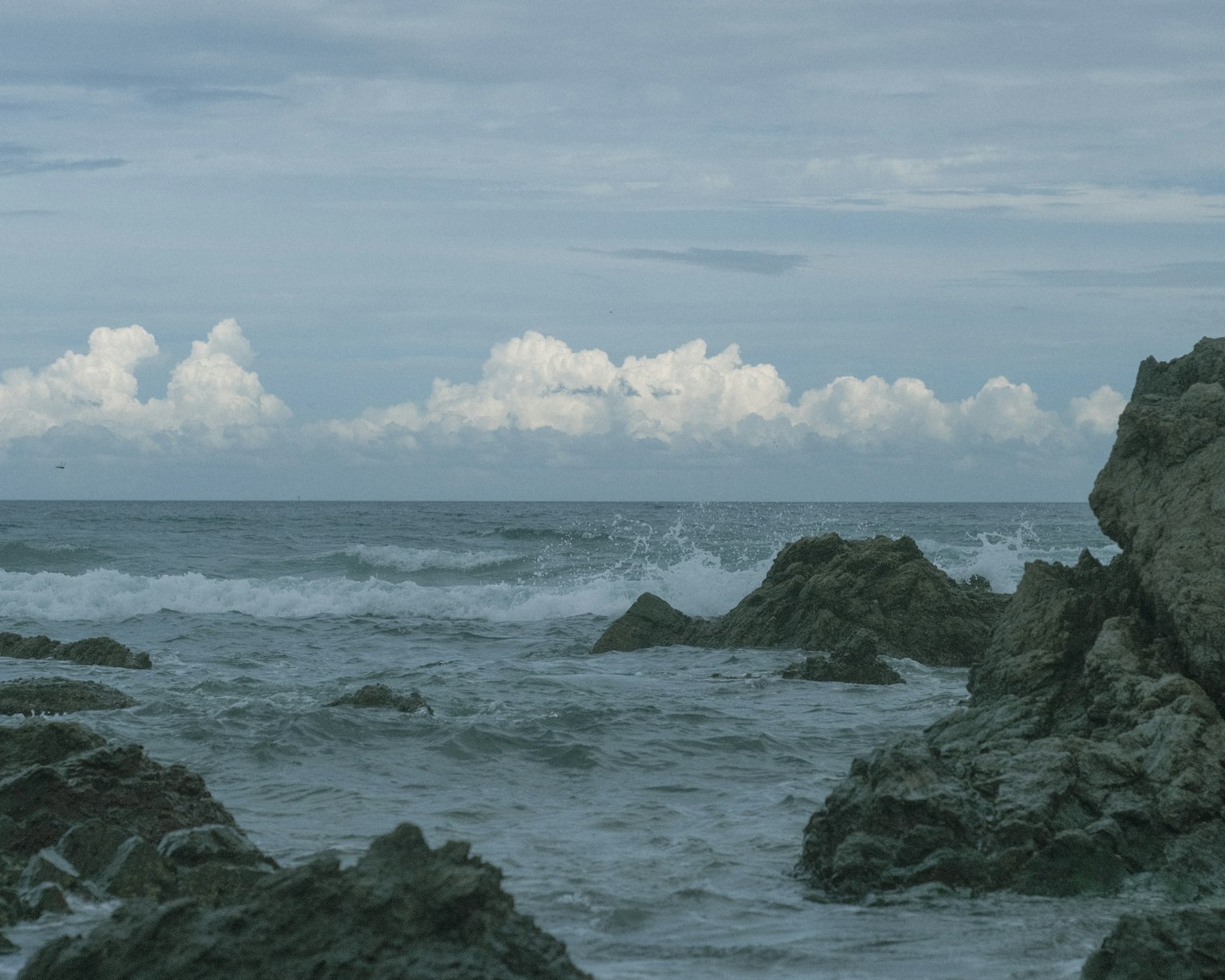 Escena costera con rocas y olas bajo un cielo azul