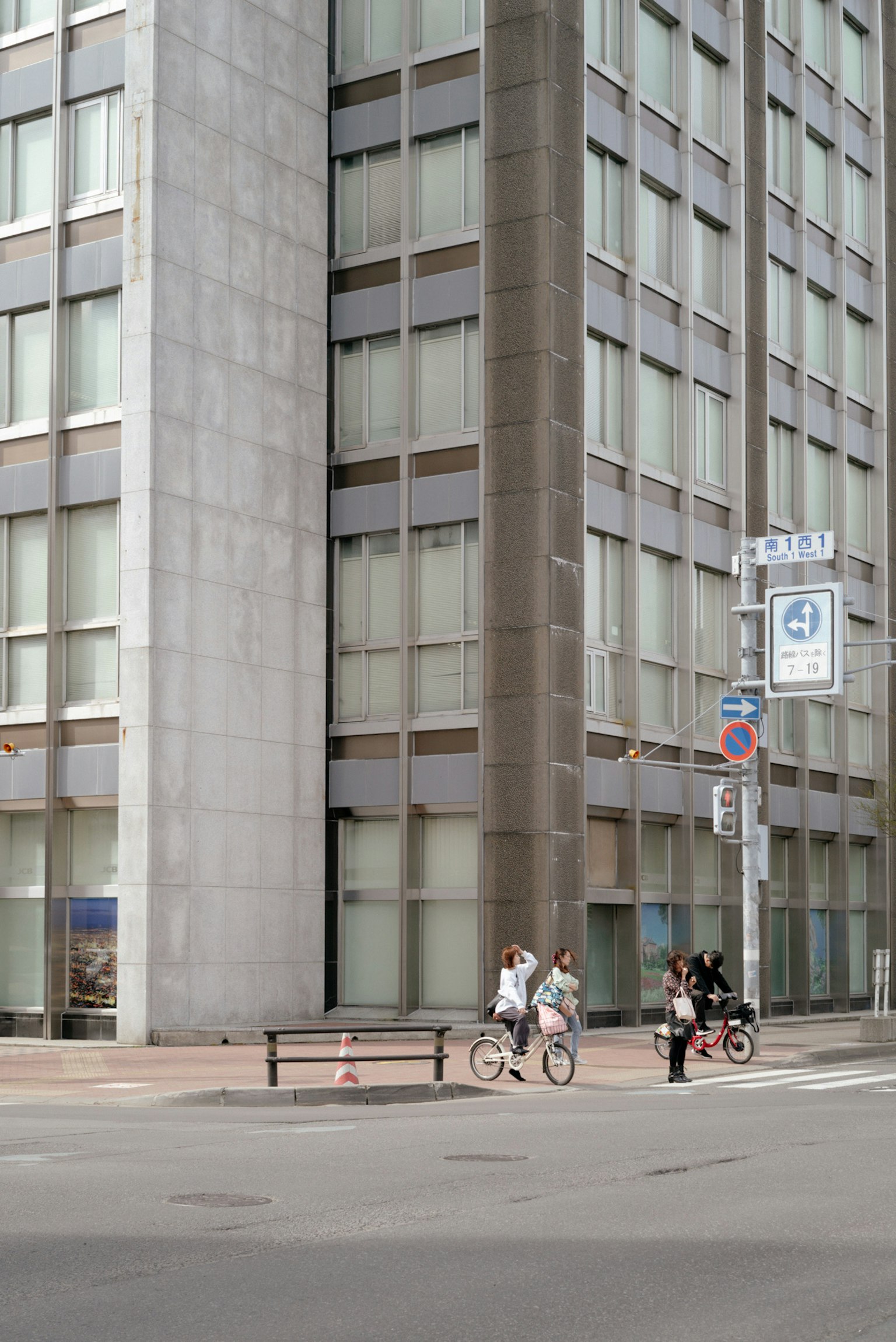 Escena urbana con un edificio y personas montando bicicletas en una intersección