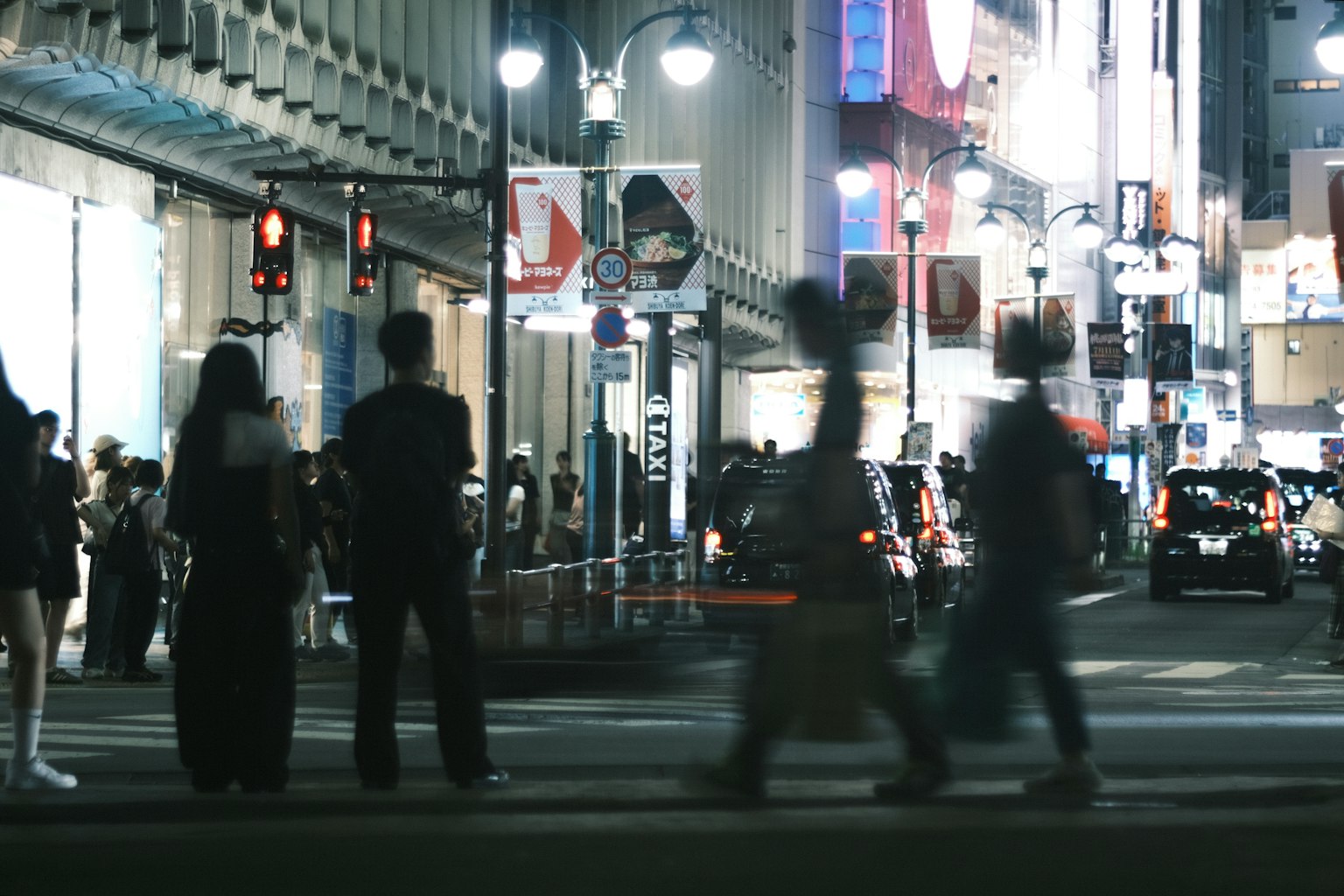 Menschen warten an einer Ampel an einer belebten städtischen Kreuzung bei Nacht
