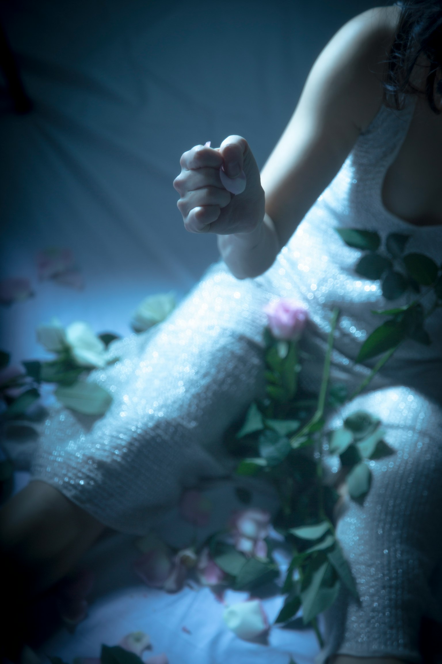 在藍光中被花瓣和葉子包圍的女性手
