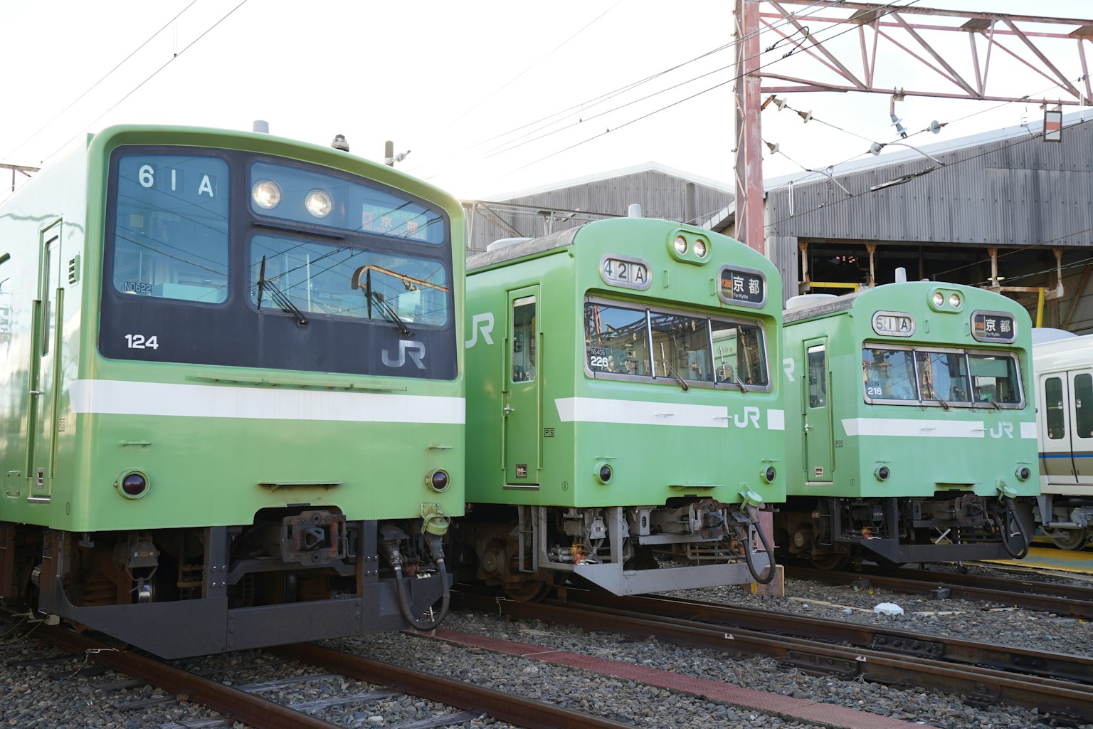 Tres trenes japoneses verdes estacionados en las vías