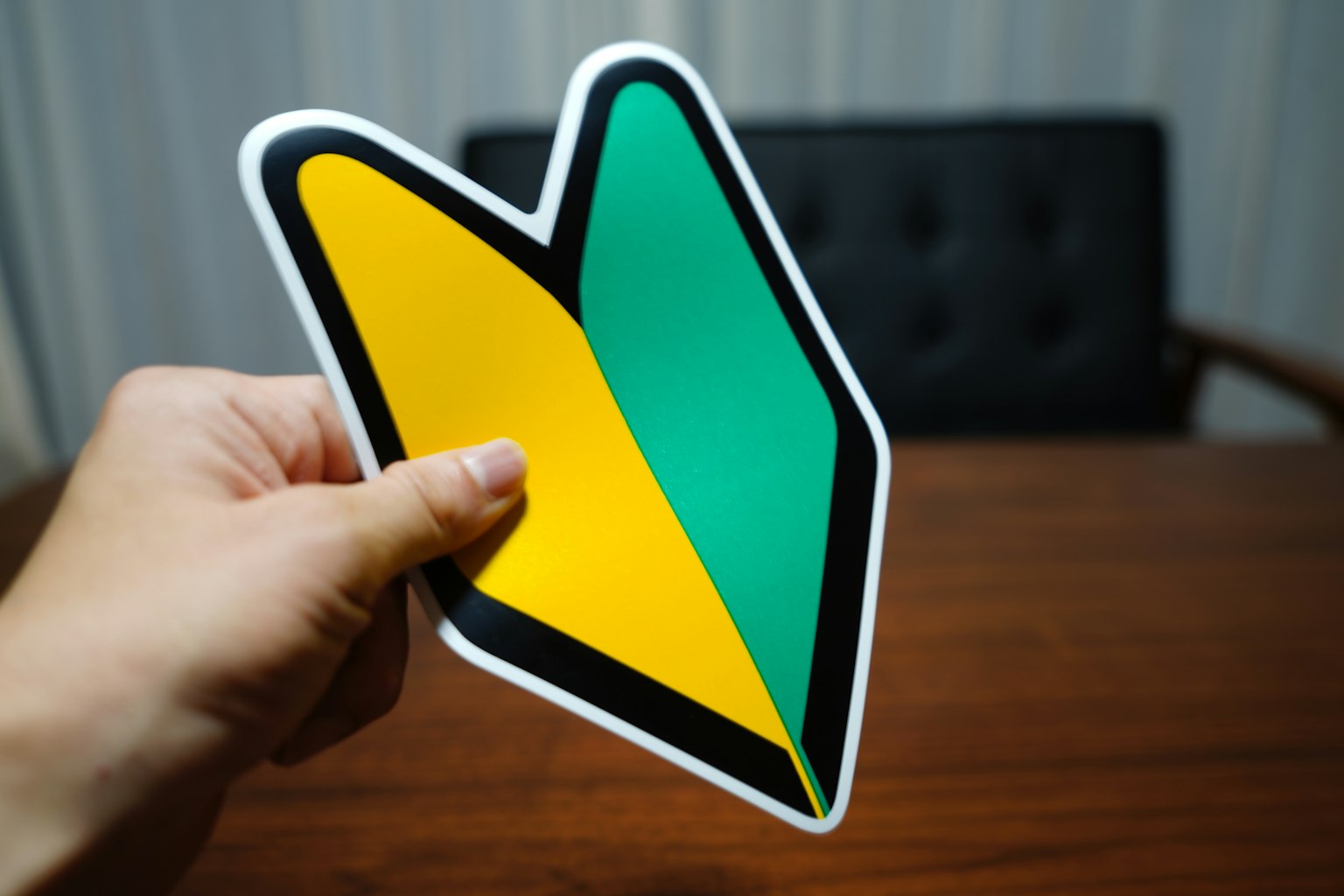 Une main tenant un autocollant en forme de flèche jaune et verte avec une table en bois en arrière-plan