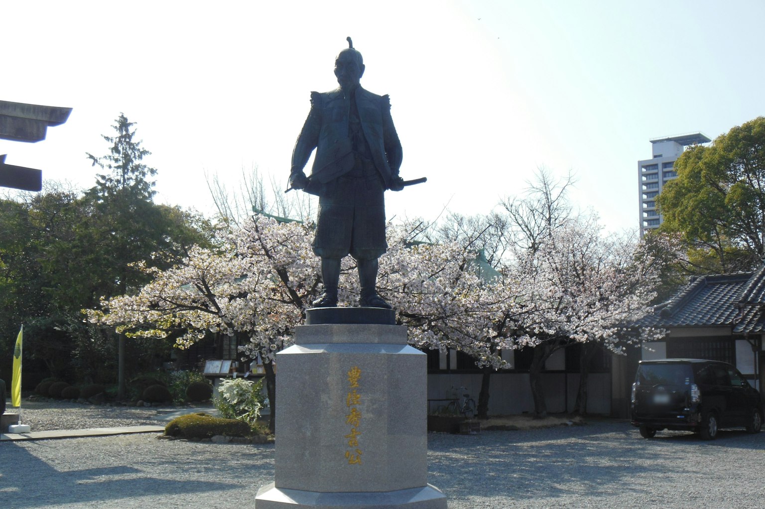 Estatua de bronce de un samurái frente a cerezos en flor