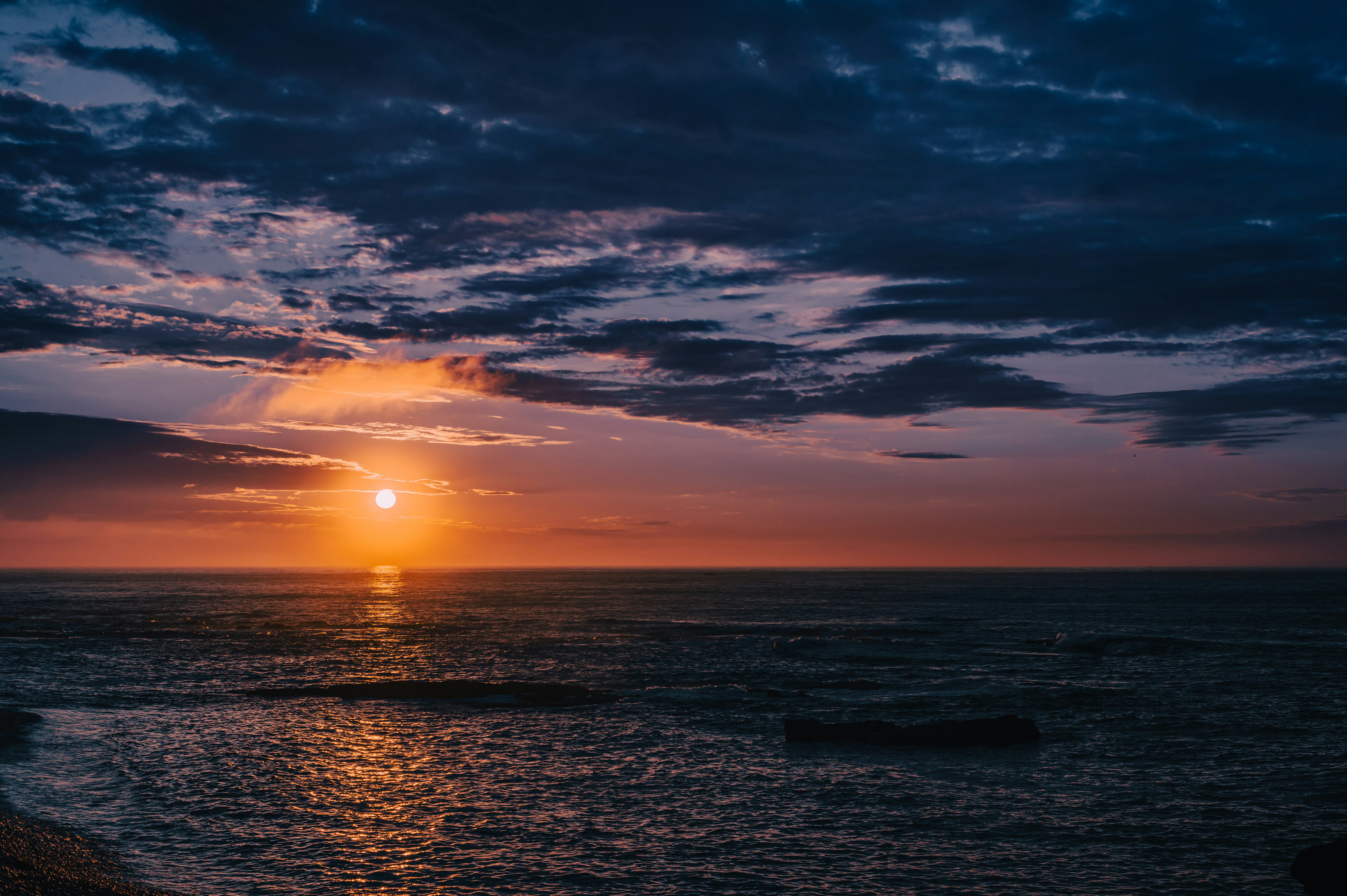 海に沈む太陽と紫・オレンジの空の夕焼け