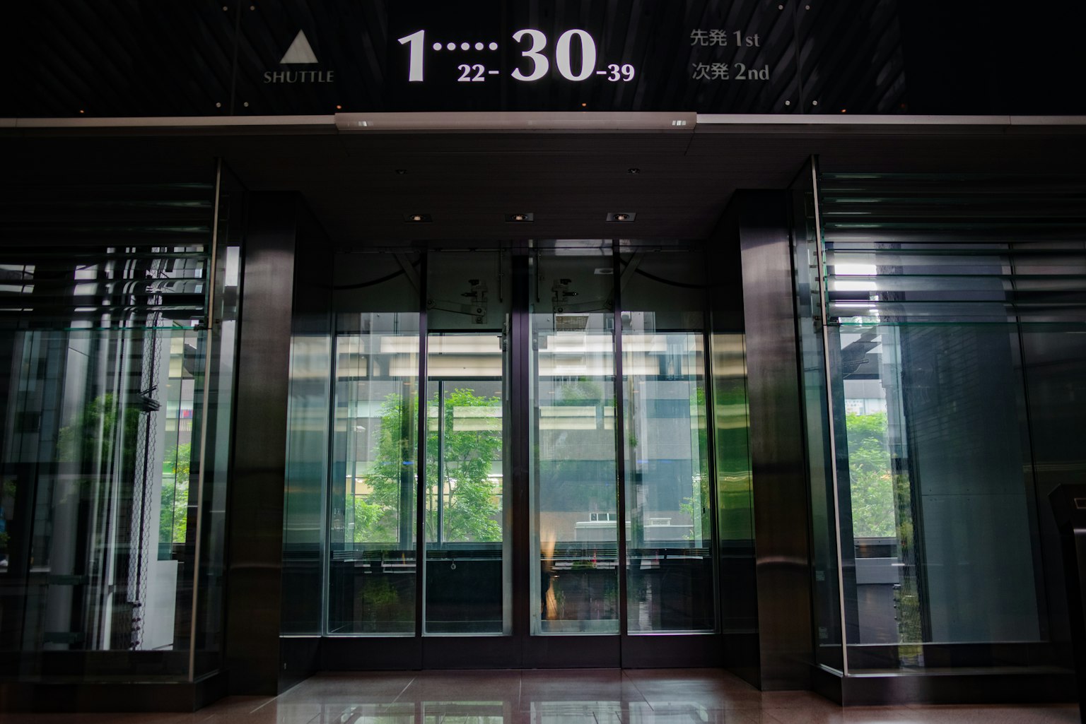 Glass elevator entrance with surrounding greenery