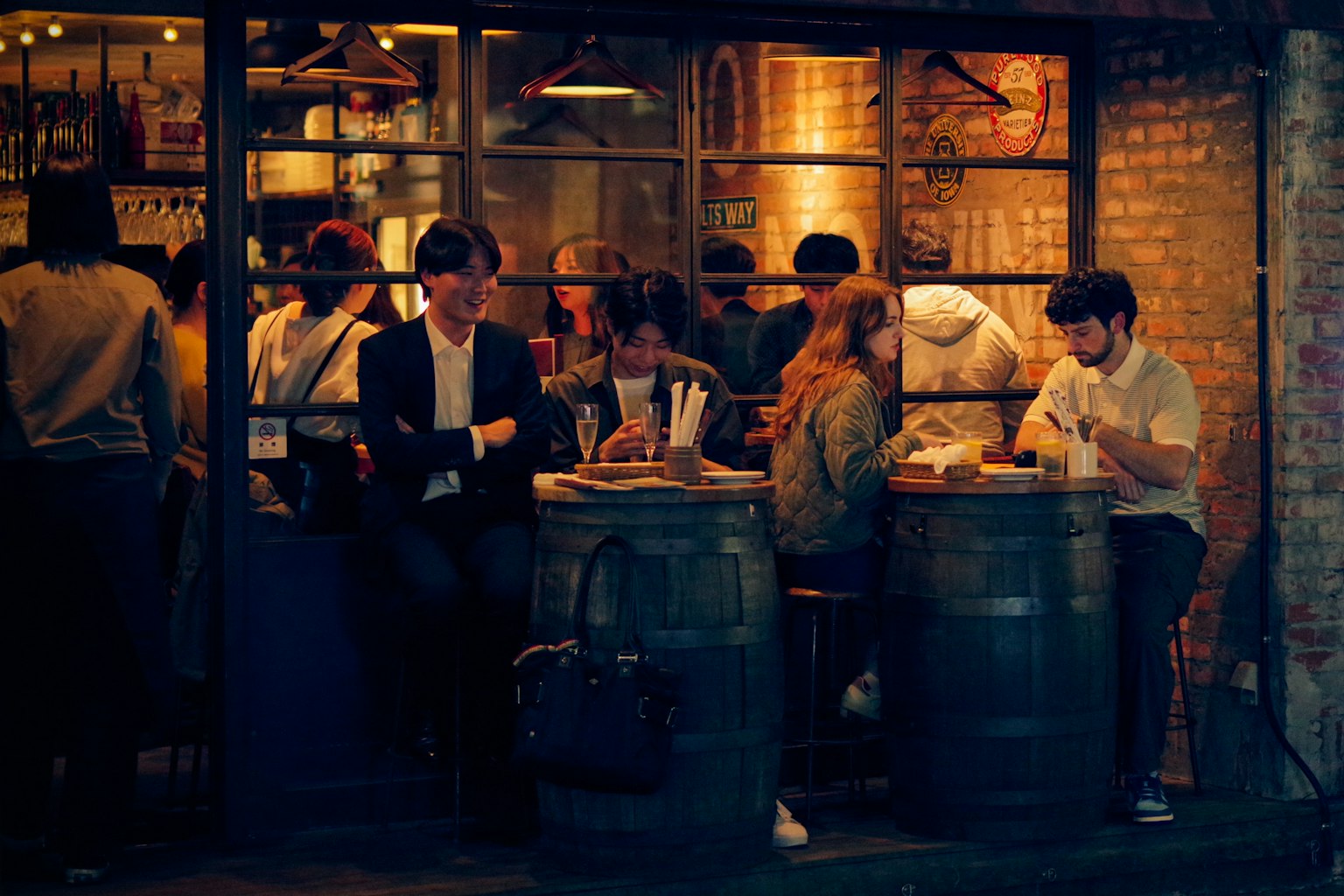 People dining outside a bar with warm lighting and a casual atmosphere