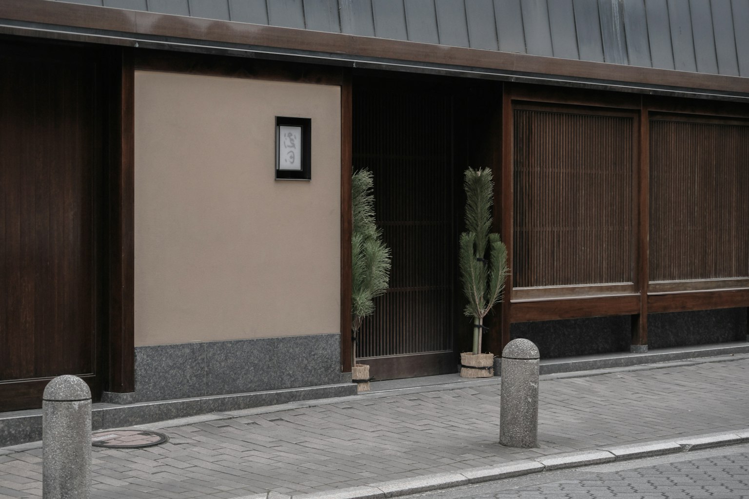 Entrance of a traditional Japanese building featuring wooden walls and greenery