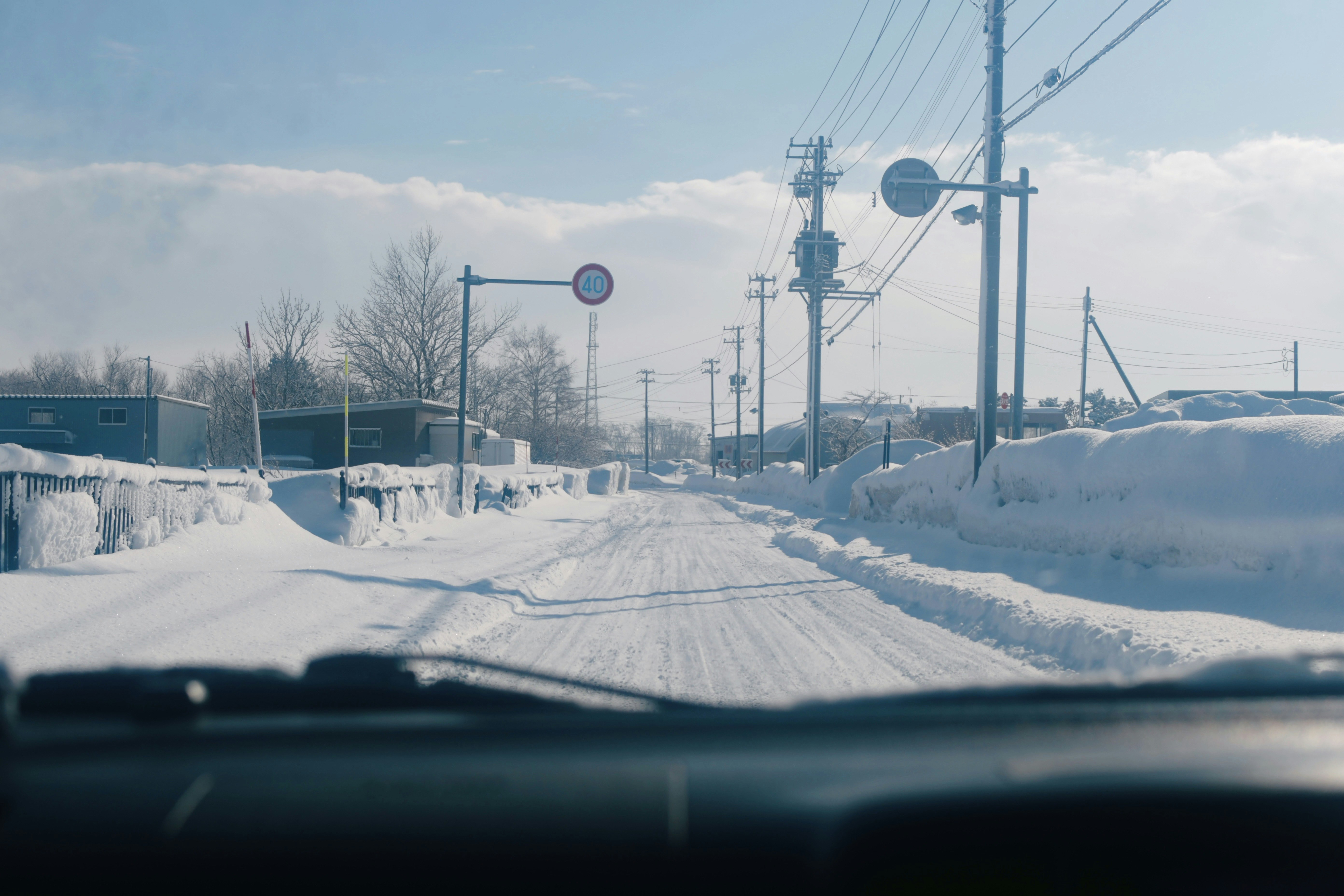 雪道を走る車のフロント越しの冬の道路風景