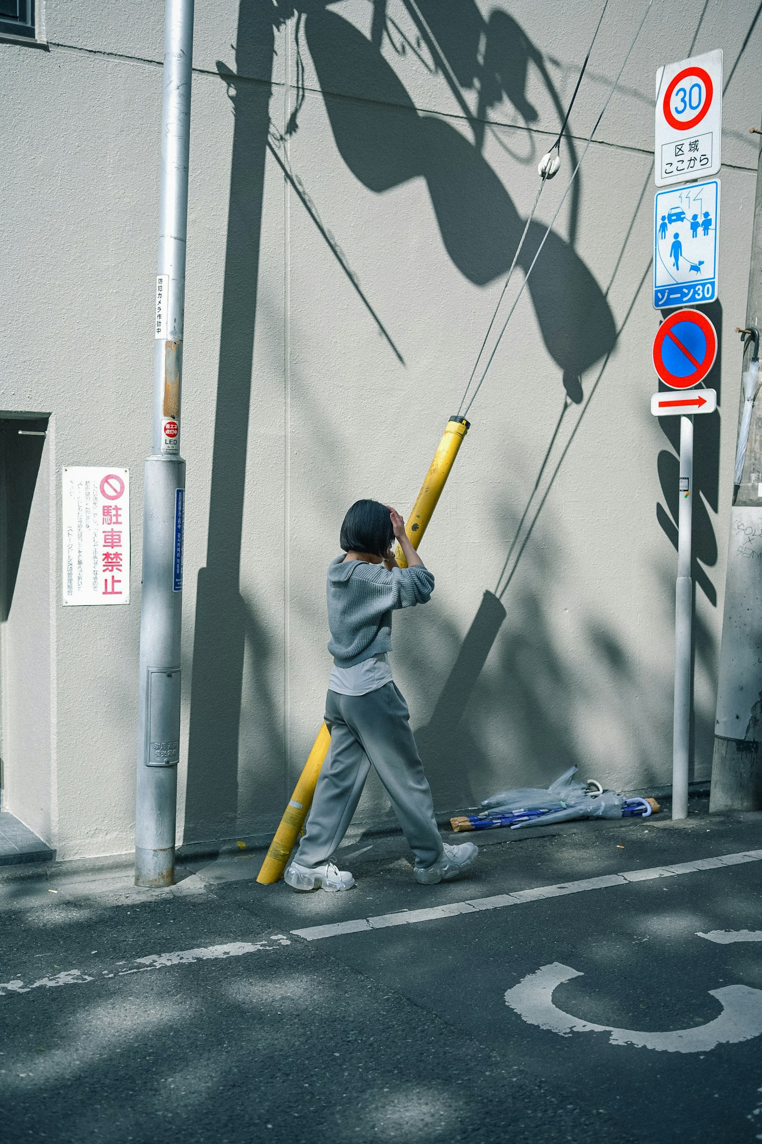 Personne marchant avec un poteau jaune projetant une ombre sur un mur