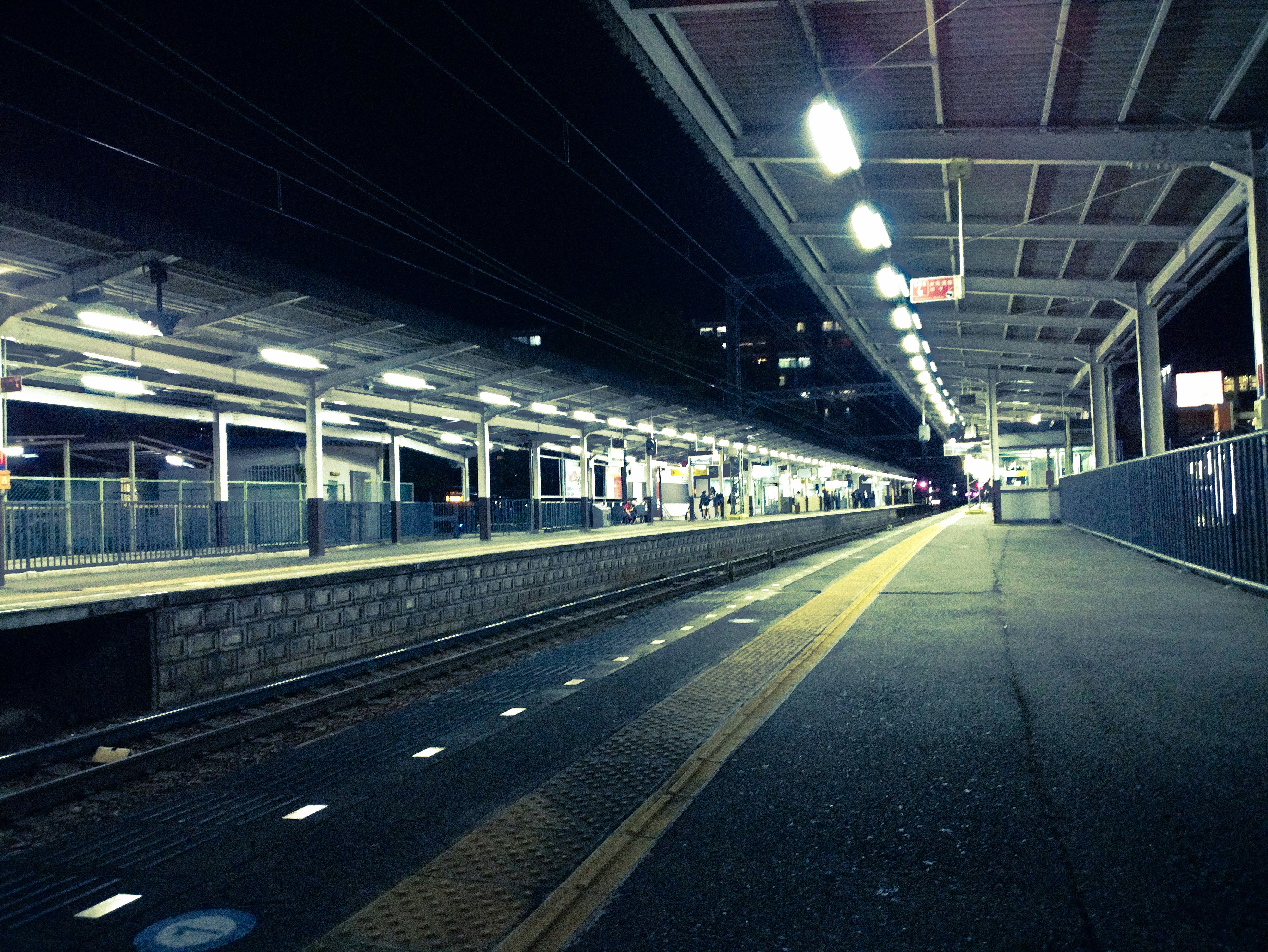 Bahnhofsbahnsteig bei Nacht mit Gleisen in die Ferne