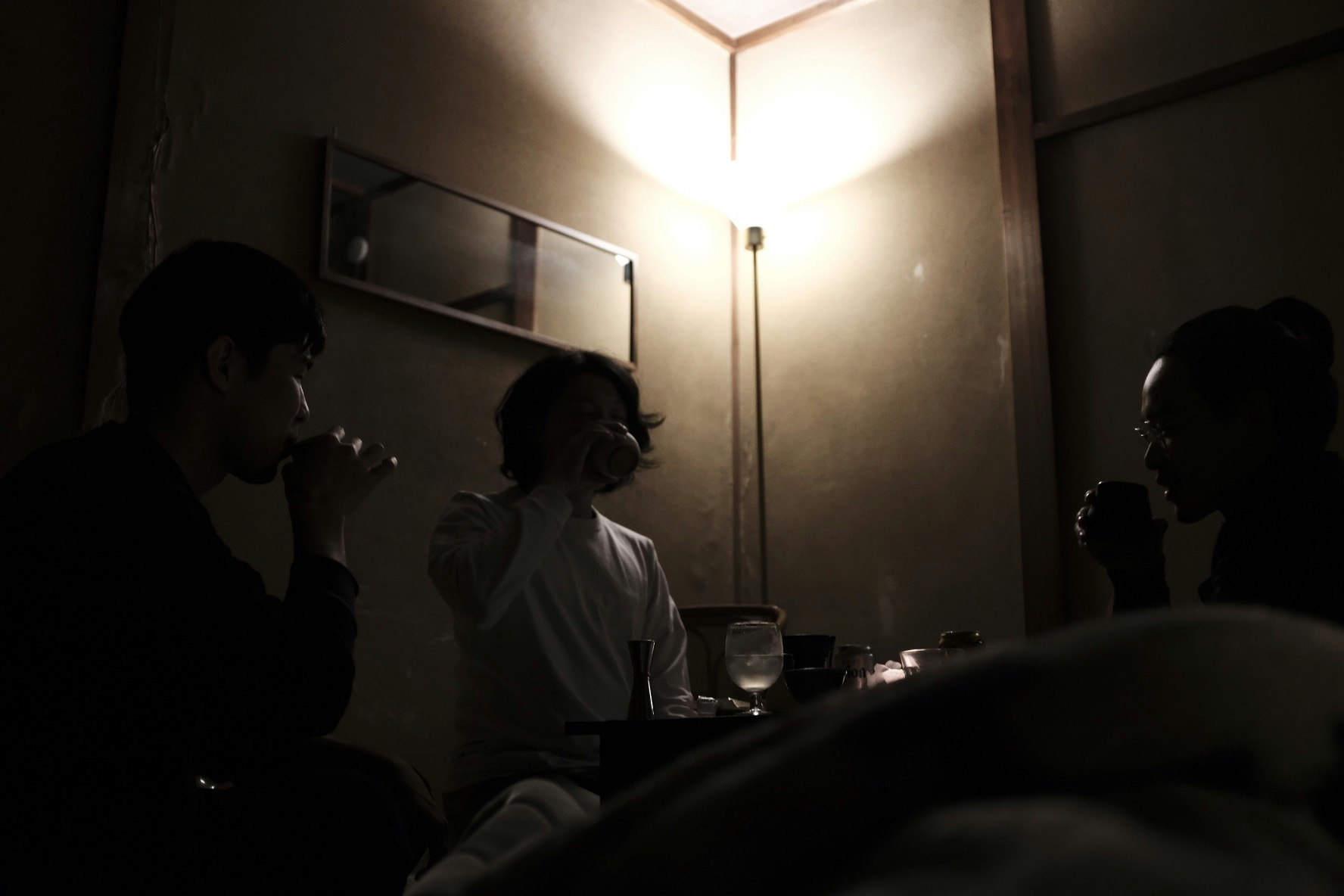 薄暗い室内でお茶を囲む人々の気配